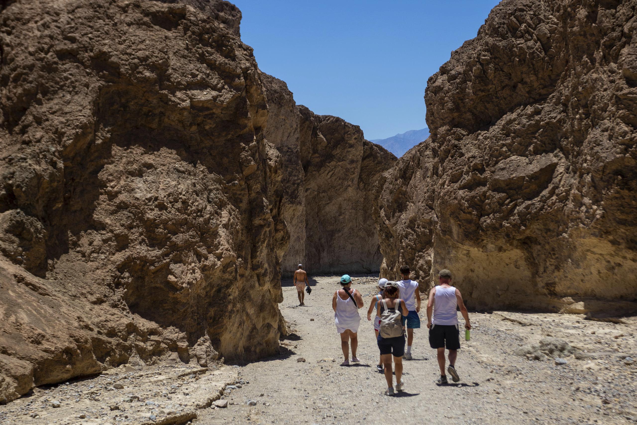 Varios excursionistas regresan a sus vehículos luego de recorrer parte del cañón Golden en el Parque Nacional Valle de la Muerte, California, el martes 11 de julio de 2023. Julio es el mes más caluroso en el parque, con una temperatura máxima promedio de 116 grados Fahrenheit. (AP Foto/Ty ONeil)