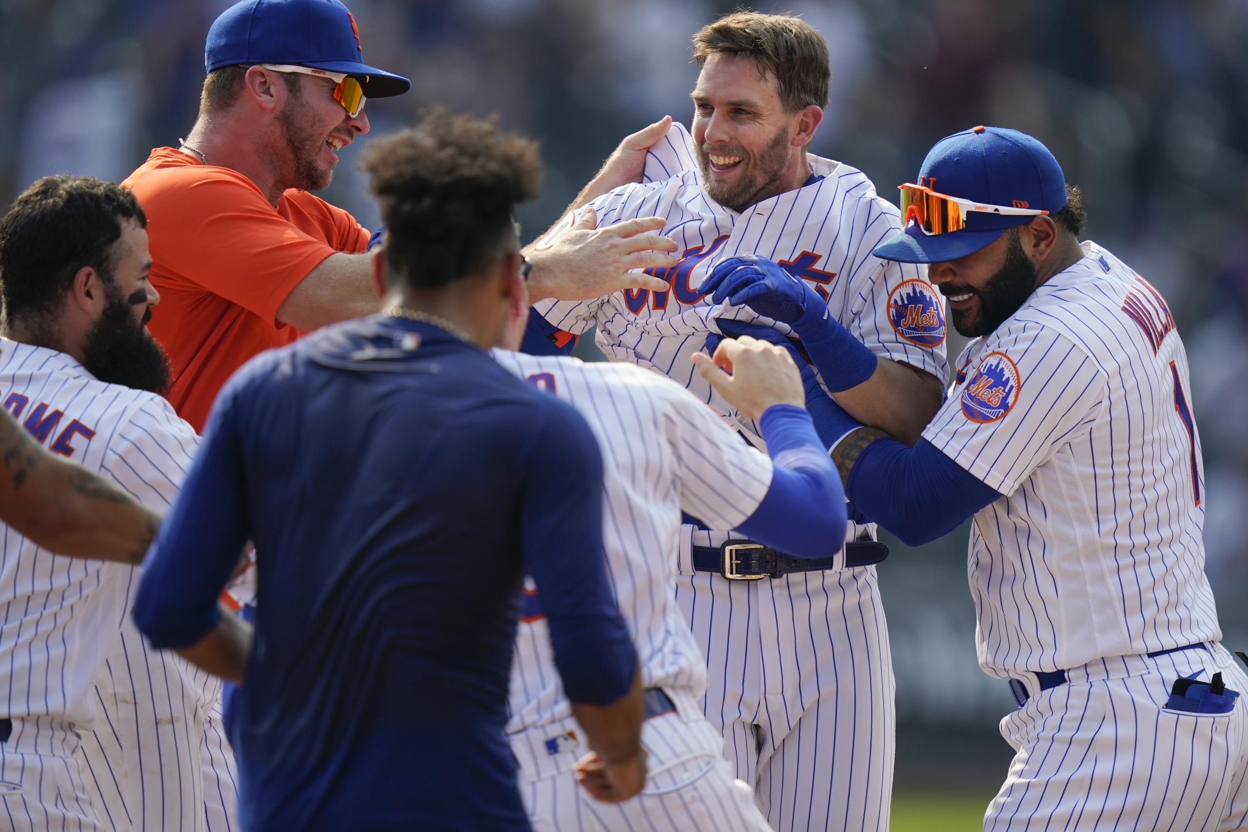 Jeff McNeil, segundo desde la derecha, es felicitado por sus compañeros de los Mets luego de conectar el hit que les dio la victoria el miércoles en el primer desafío de un doble juego.