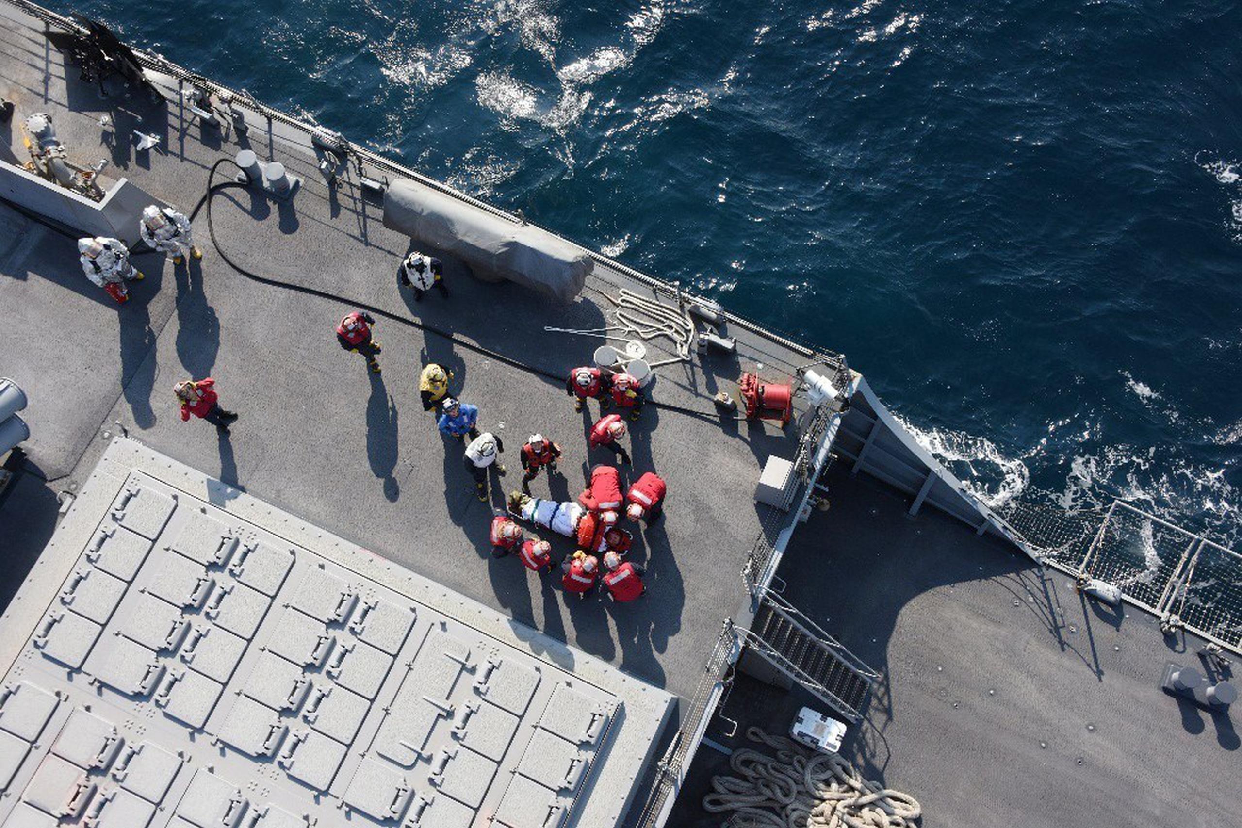 Personal de la milicia norteamericana transporta a uno de los marinos heridos en el accidente del buque. (EFE)