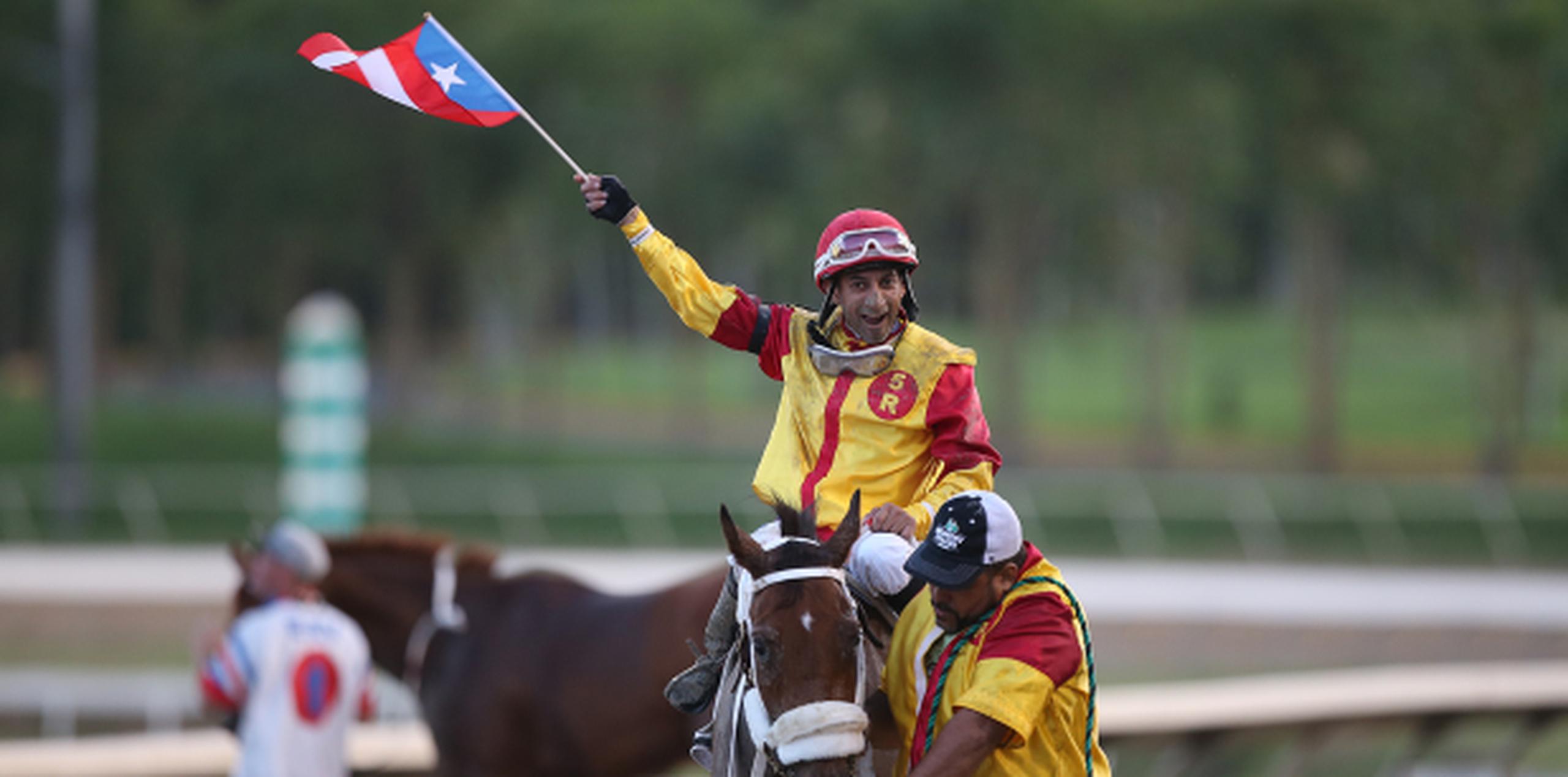 El jinete Edwin Castro celebra el triunfo con la bandera de Puerto Rico. (Foto/José Cruz Candelaria)