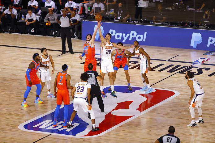 Mike Muscala (33) del Thunder y Dario Saric (20) de los Suns saltan al inicio del partido del lunes. Phoenix logró en el partido su sexto triunfo en línea, para mantenerse invicto en la 'burbuja' de la NBA.