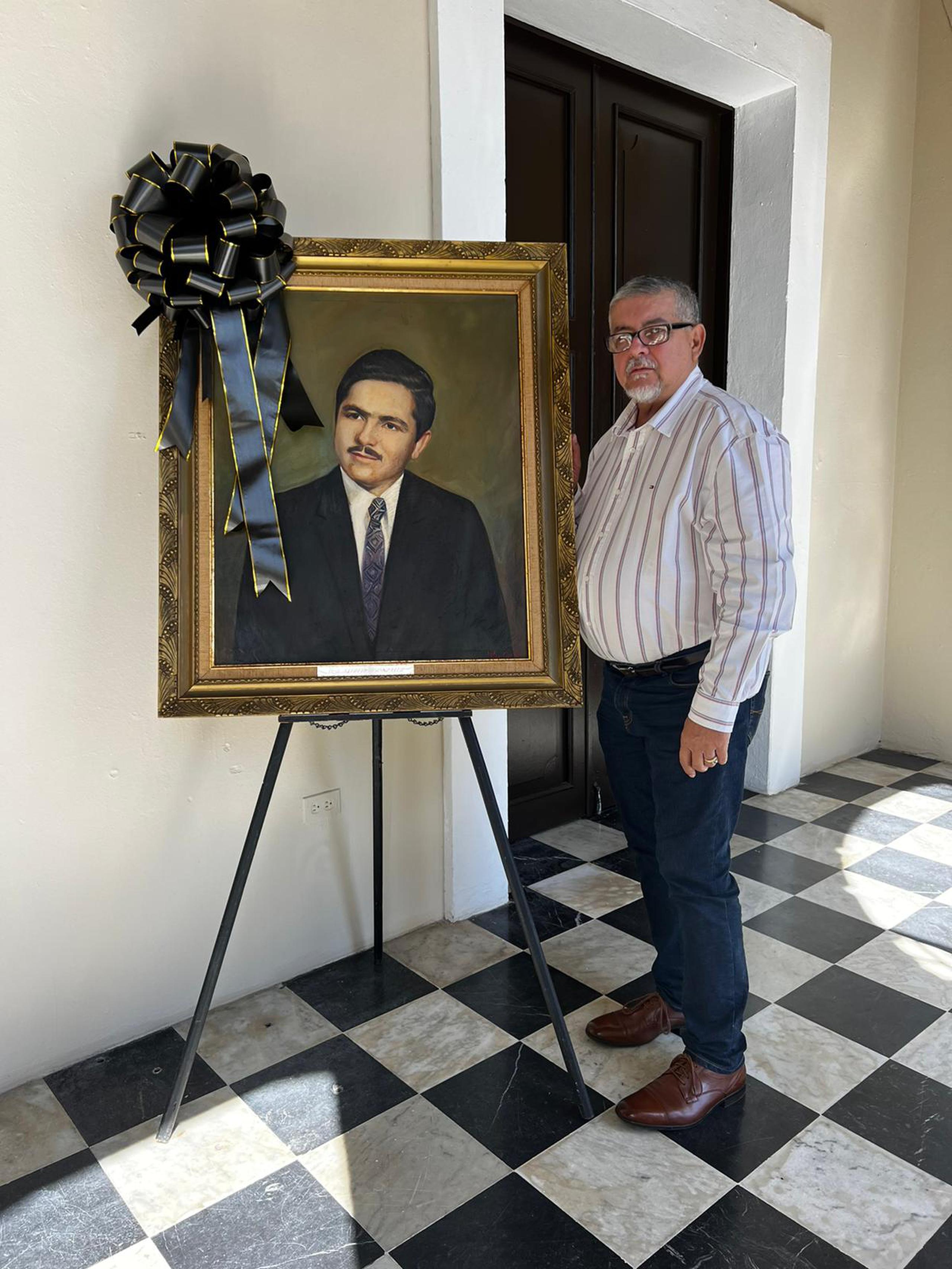 El alcalde de Arecibo, Carlos “Tito” Ramírez Irizarry justo al lado de un cuadro del exalcalde Alfredo González Rivera.
