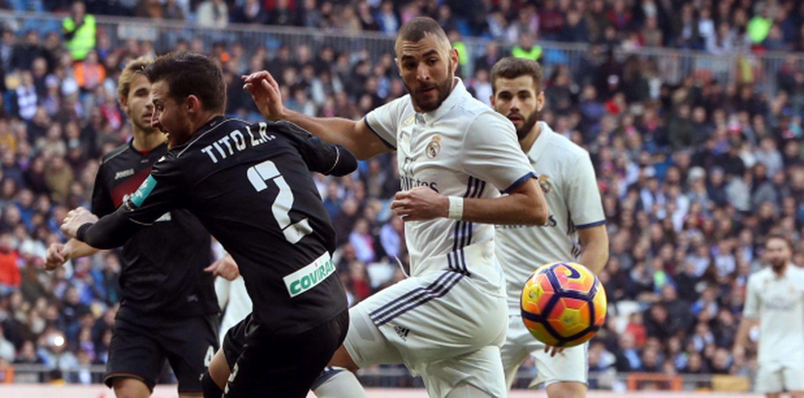 El delantero del Real Karim Benzema pelea un balón con el defensa del Granada Tito durante el partido de la décimo séptima jornada de Liga de Primera División disputado esta mañana en el estadio Santiago Bernabéu. (EFE/JJ Guillén)