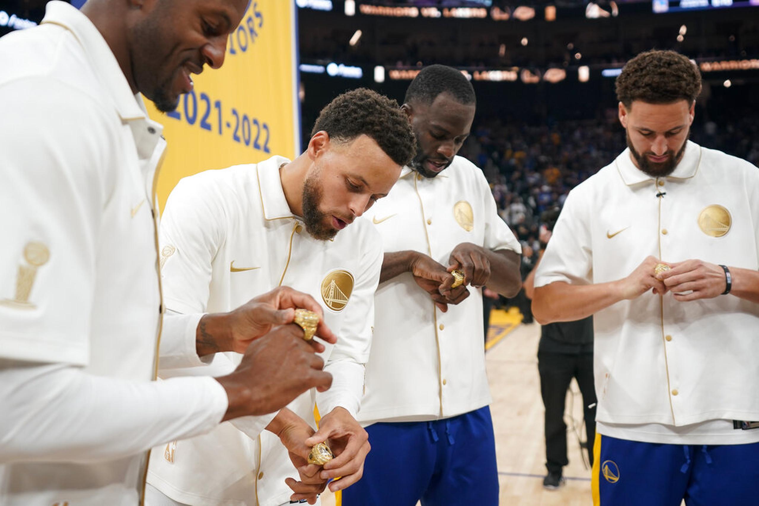 Andre Iguodala, Stephen Curry, Draymond Green y Klay Thompson de los Warriors miran sus anillos del campeonato 2021-2022 antes del partido contra los Lakers en San Francisco, el 18 de octubre de 2022.