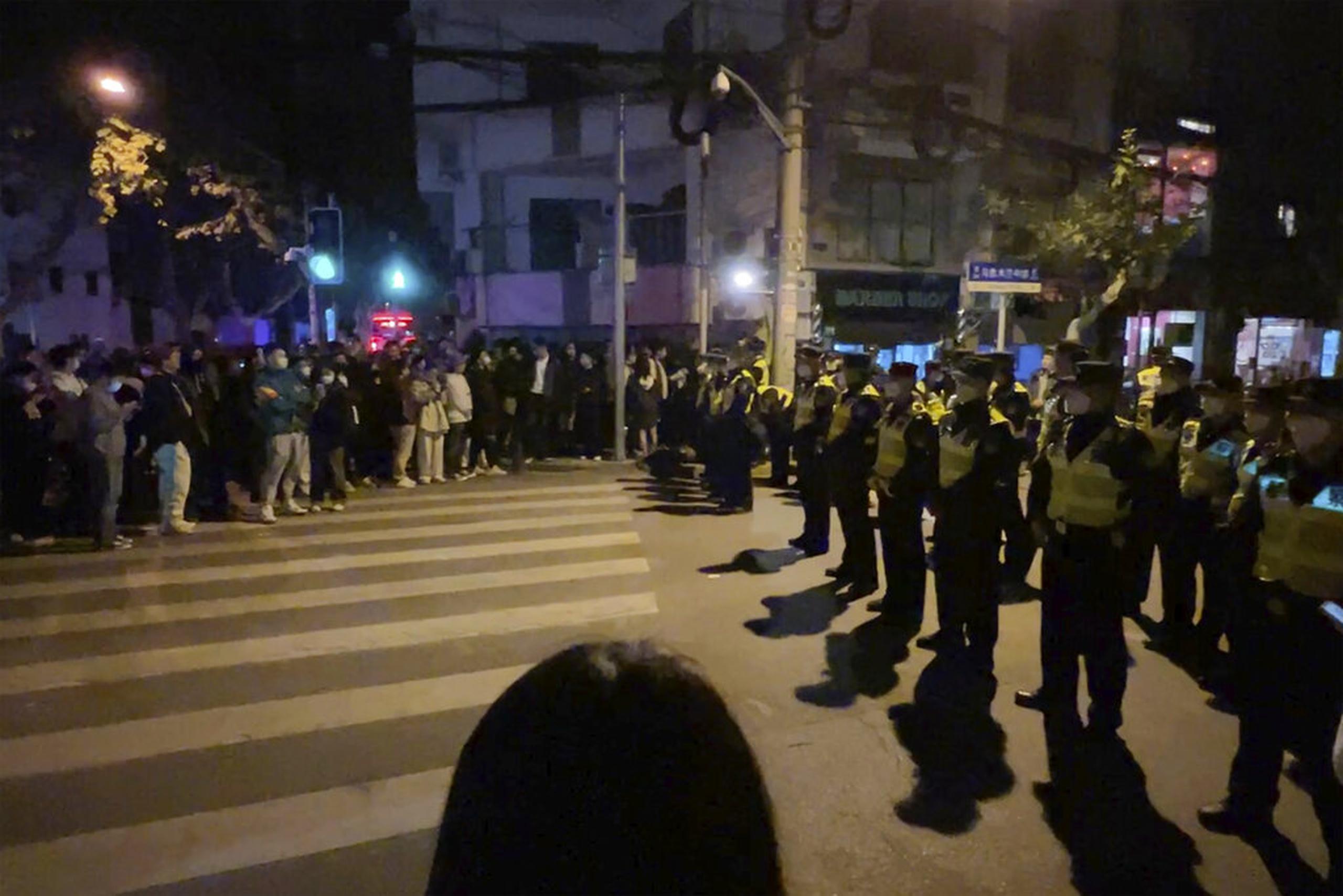 Policías chinos bloquean el acceso a un sitio donde los manifestantes se habían reunido en Shanghái el 27 de noviembre de 2022.