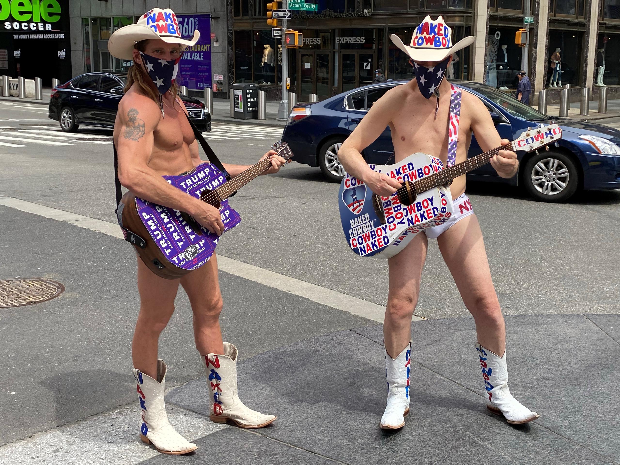 Dos personas disfrazadas como el famoso personaje de Times Square "Naked Cowboy" (Vaquero Desnudo), llevan un pañuelo tapaboca con la estrellas de la bandera nacional este fin de semana en una calle de Nueva York.
