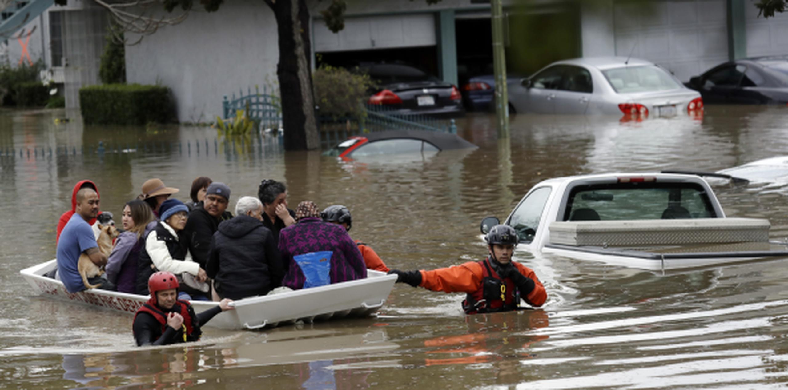 Rescatistas de equipos de emergencia socorren a varias personas y mascotas en un barrio de San José que quedó bajo las aguas que se desbordaron de un arroyo cercano. (AP/Marcio Jose Sanchez)
