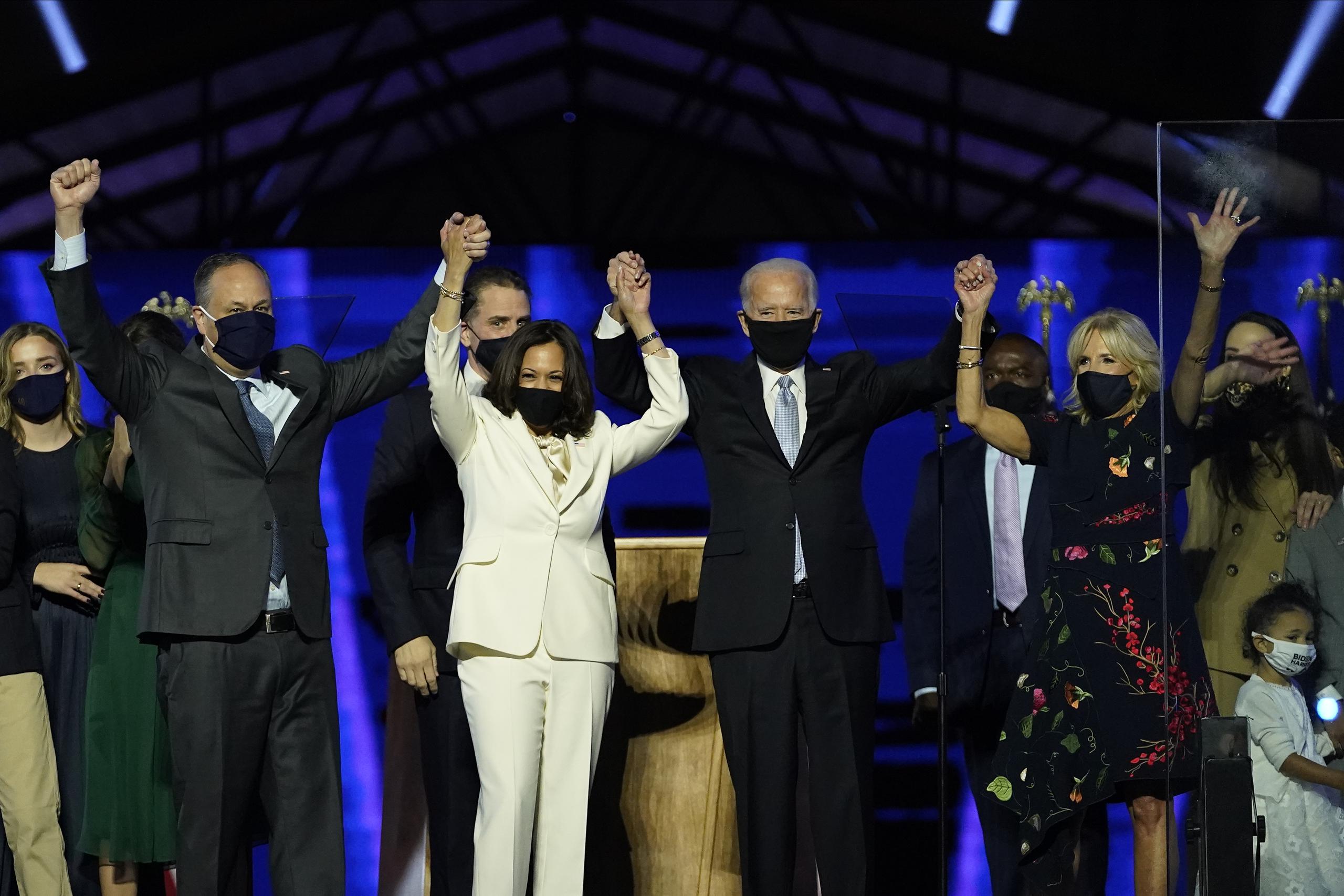De izquierda a derecha, Doug Emhoff, esposo de la vicepresidenta electa Kamala Harris, Harris, el presidente electo Joe Biden y su esposa Jill Biden se despiden de los partidarios desde el escenario, en Wilmington, Delaware.