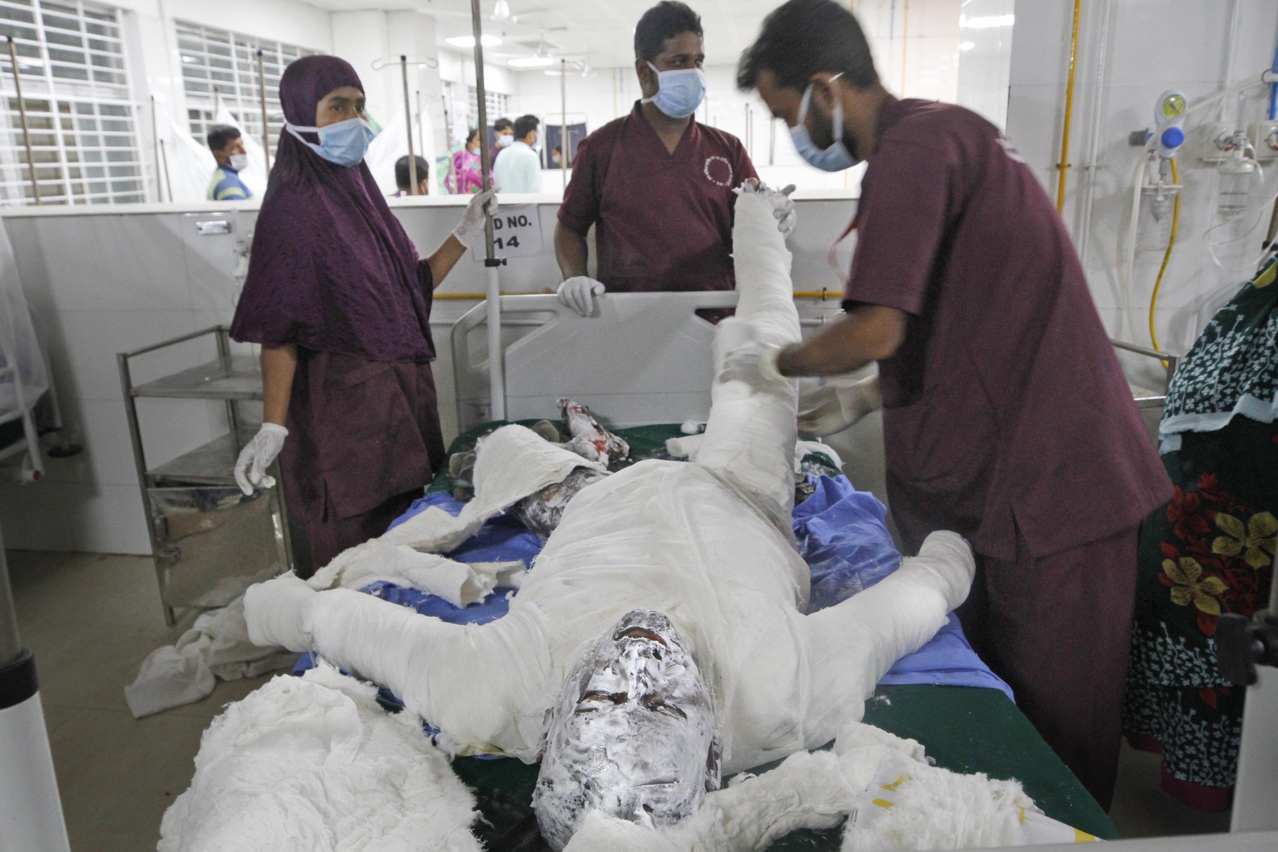 Varios médicos atienden a una persona que se quemó al estallar un gasoducto junto a la mezquita en la que se encontraba, en Daca, Bangladesh.