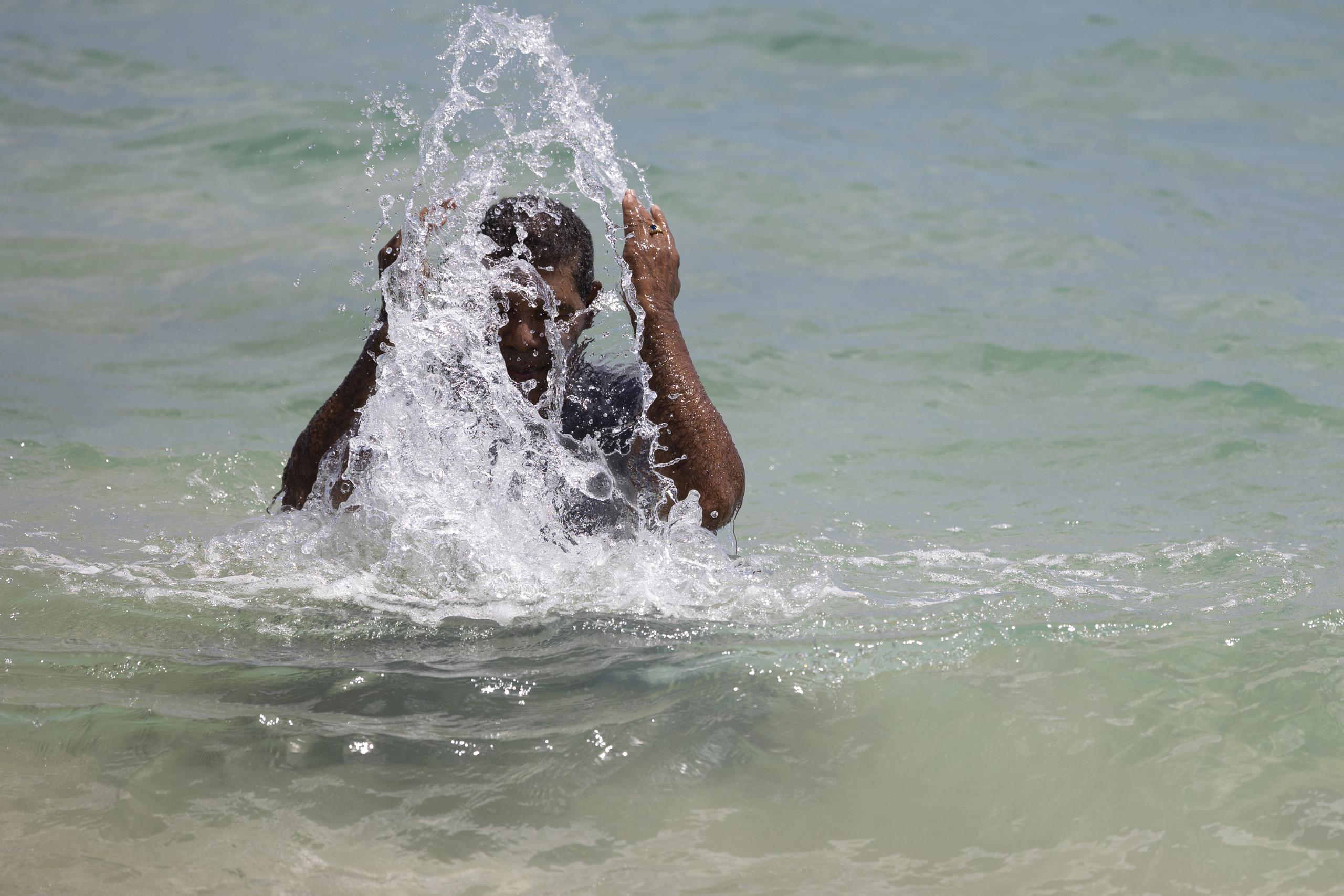 Un hombre se refresca en playa tras varios días de calor extremo.