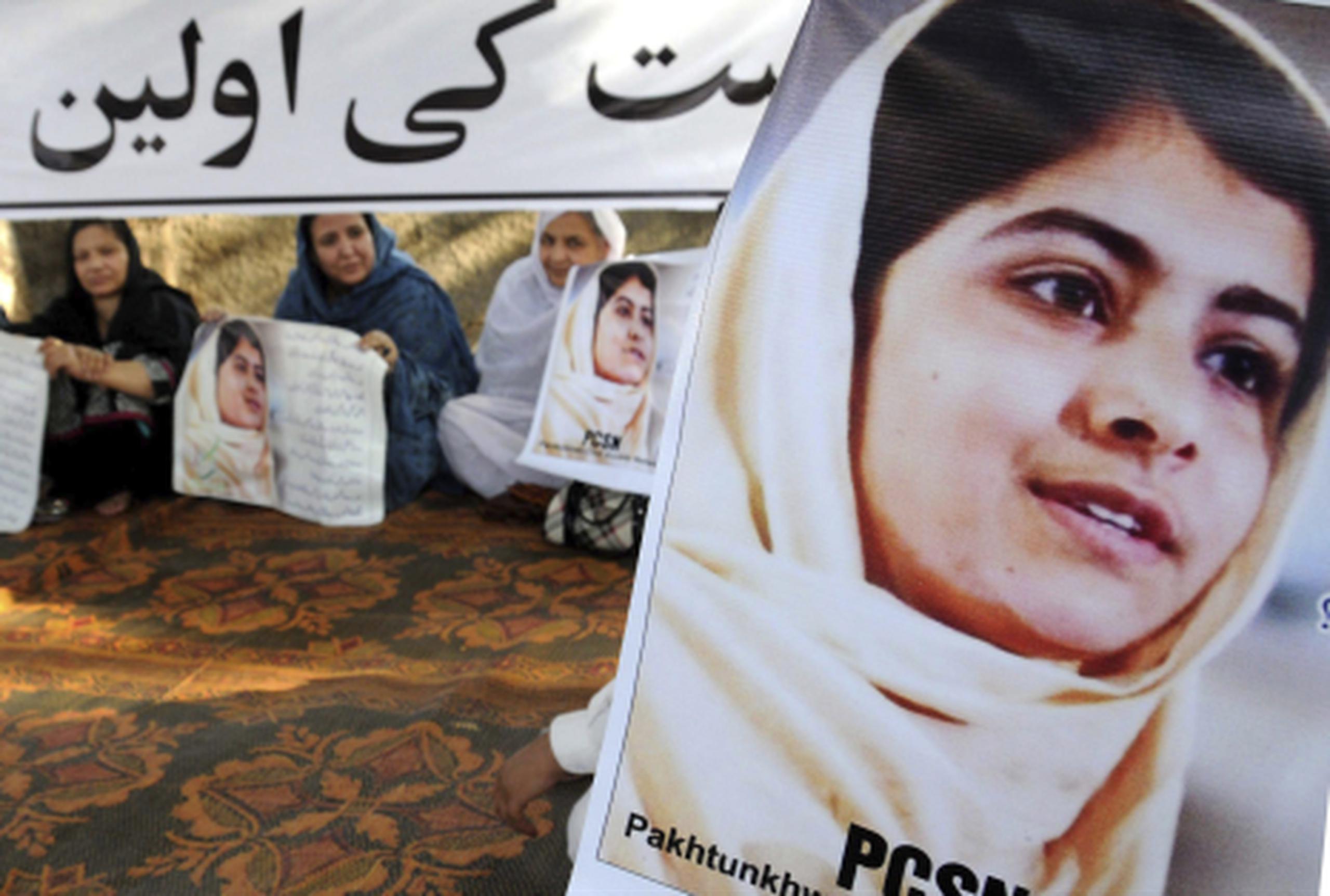 Mujeres paquistaníes sujetan carteles con el rostro de la joven activista por la paz de 14 años Malala Yusufzai. (EFE/Arshad Arbab)