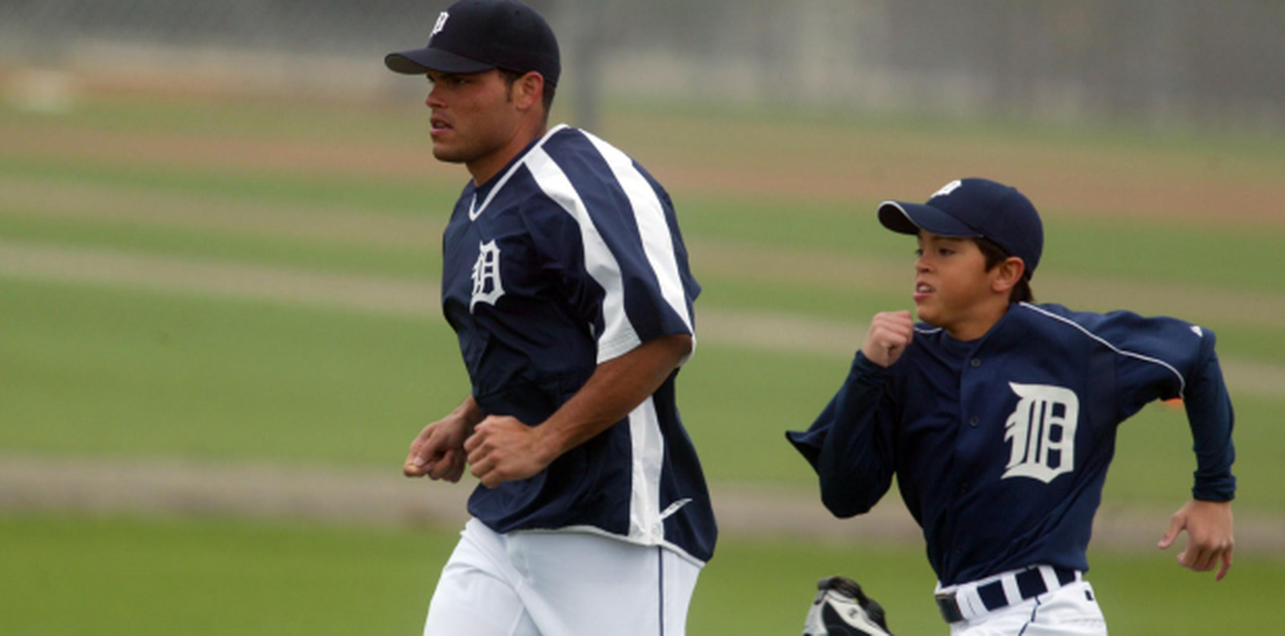 En una foto de archivo de 2005, el adolescente Dereck Iván Rodríguez corre al lado de su padre Iván en los campos primaverales de los Tigres de Detroit. (Archivo)