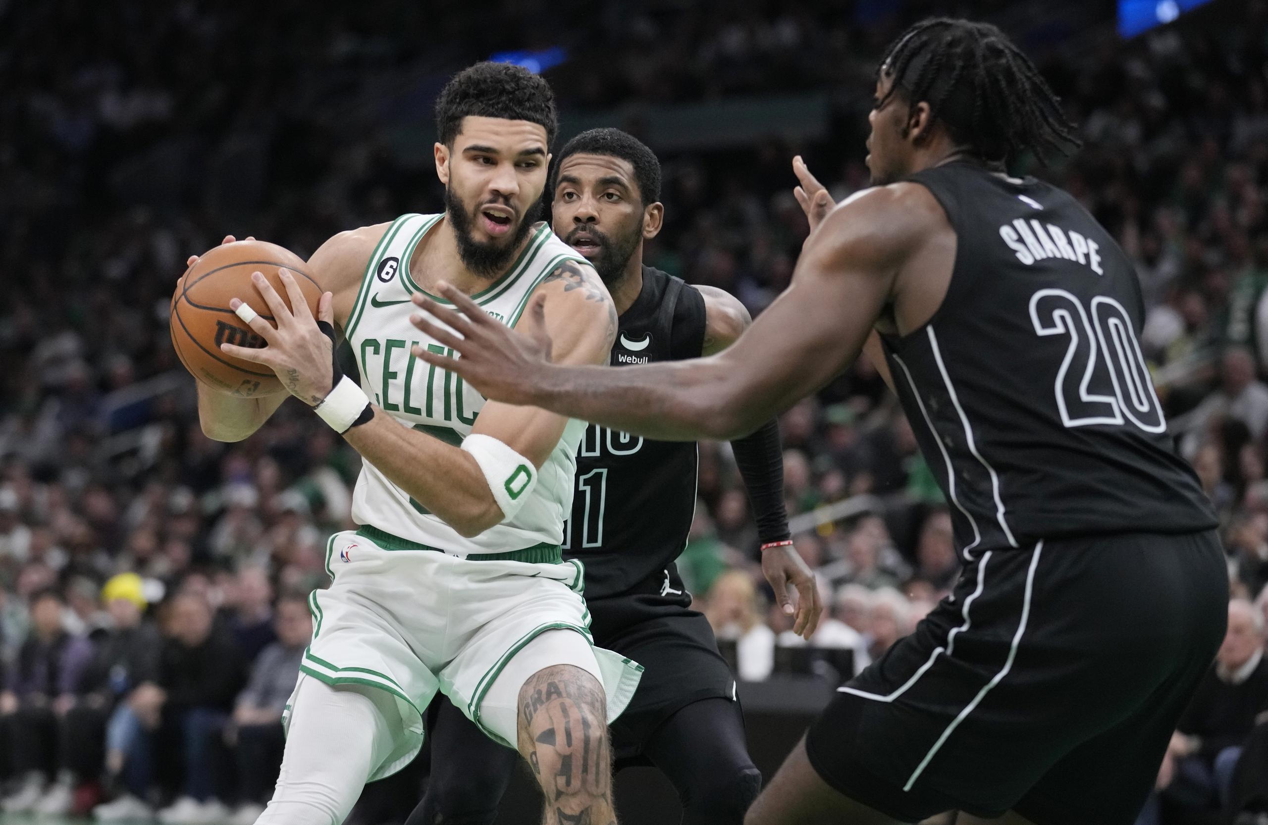 Jayson Tatum, de los Celtics de Boston, intenta pasar entre Day'ron Sharpe y Kyrie Irving, de los Nets de Brooklyn, durante el partido del miércoles.