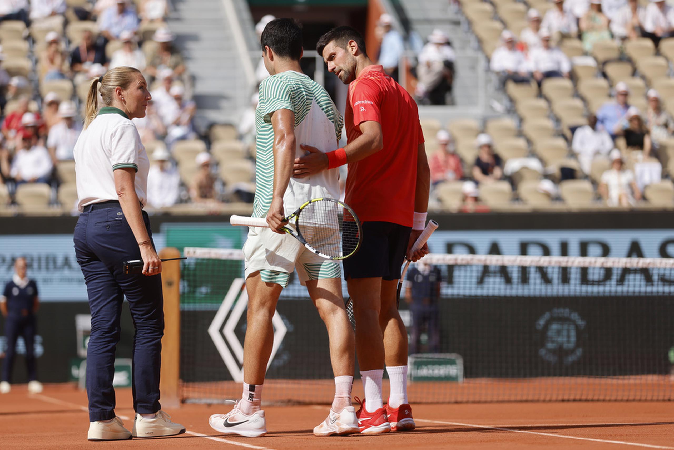 Novak Djokovic asiste el español Carlos Álcaraz al concluir el partido semifinal del Abierto de Francia.