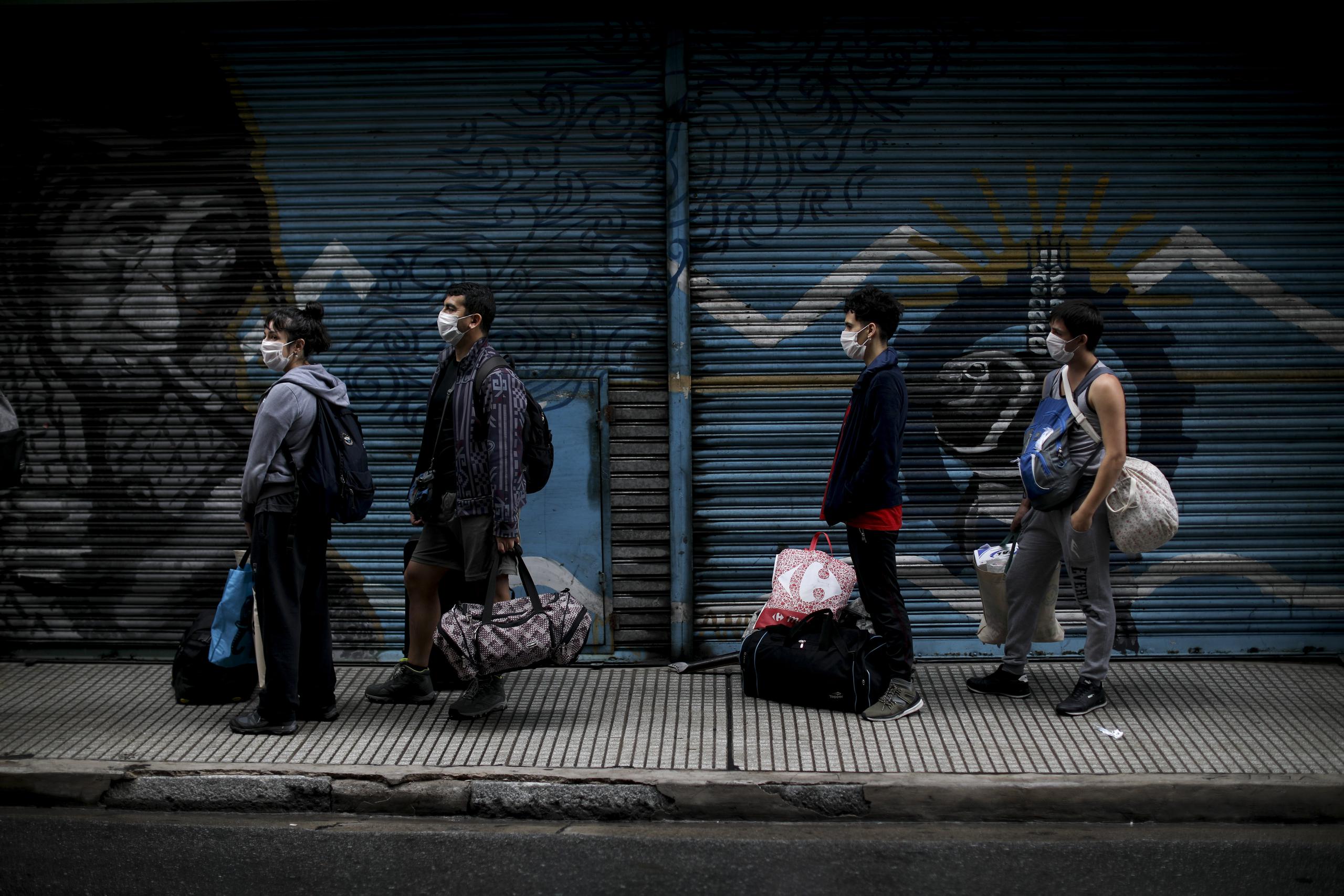 Unas personas se forman para tomarse la temperatura antes de subir a un autobús, en Buenos Aires, Argentina, el miércoles 1 de abril de 2020. (AP Foto/Natacha Pisarenko)