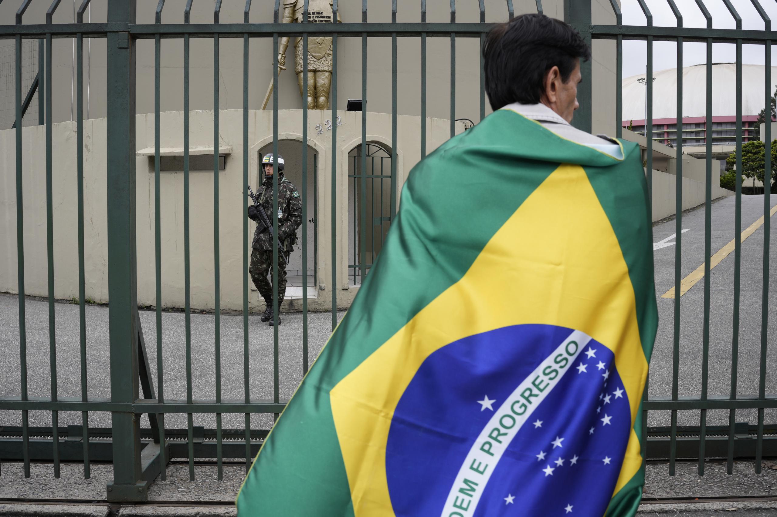 Envuelto en la bandera nacional, un partidario del presidente brasileño Jair Bolsonaro participa en una manifestación frente a una base militar para protestar por la derrota del mandatario en los comicios.