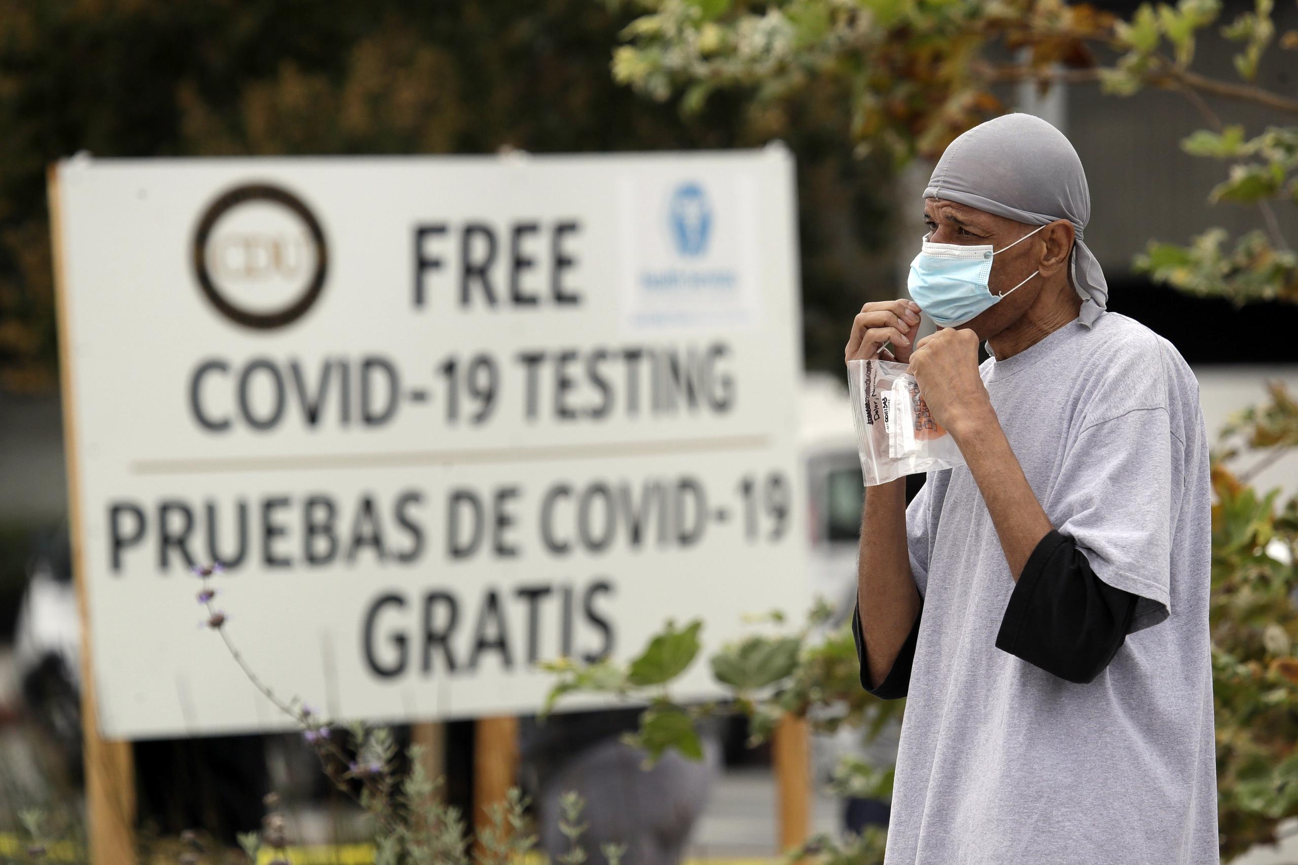 Una persona camina frente a un letrero que anuncia, en español e inglés, pruebas gratuitas de COVID-19 en Los Ángeles.