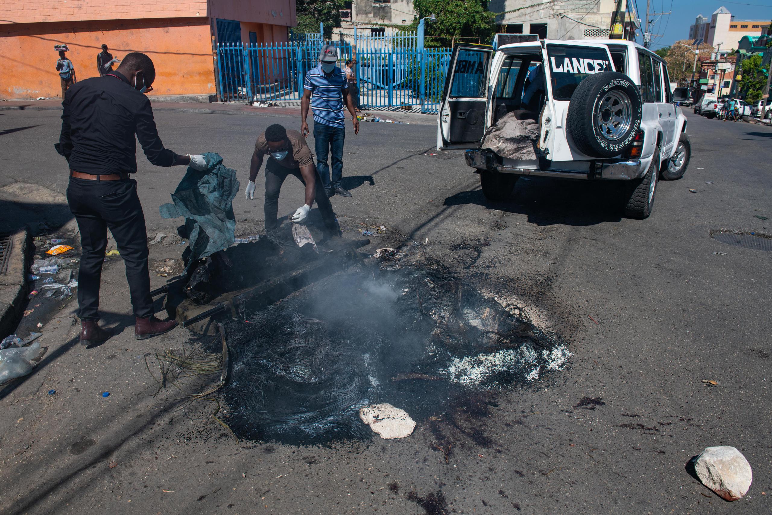 Empleados municipales recogen los restos de un cadáver carbonizado hallado en una calle de Puerto Príncipe (Haití).