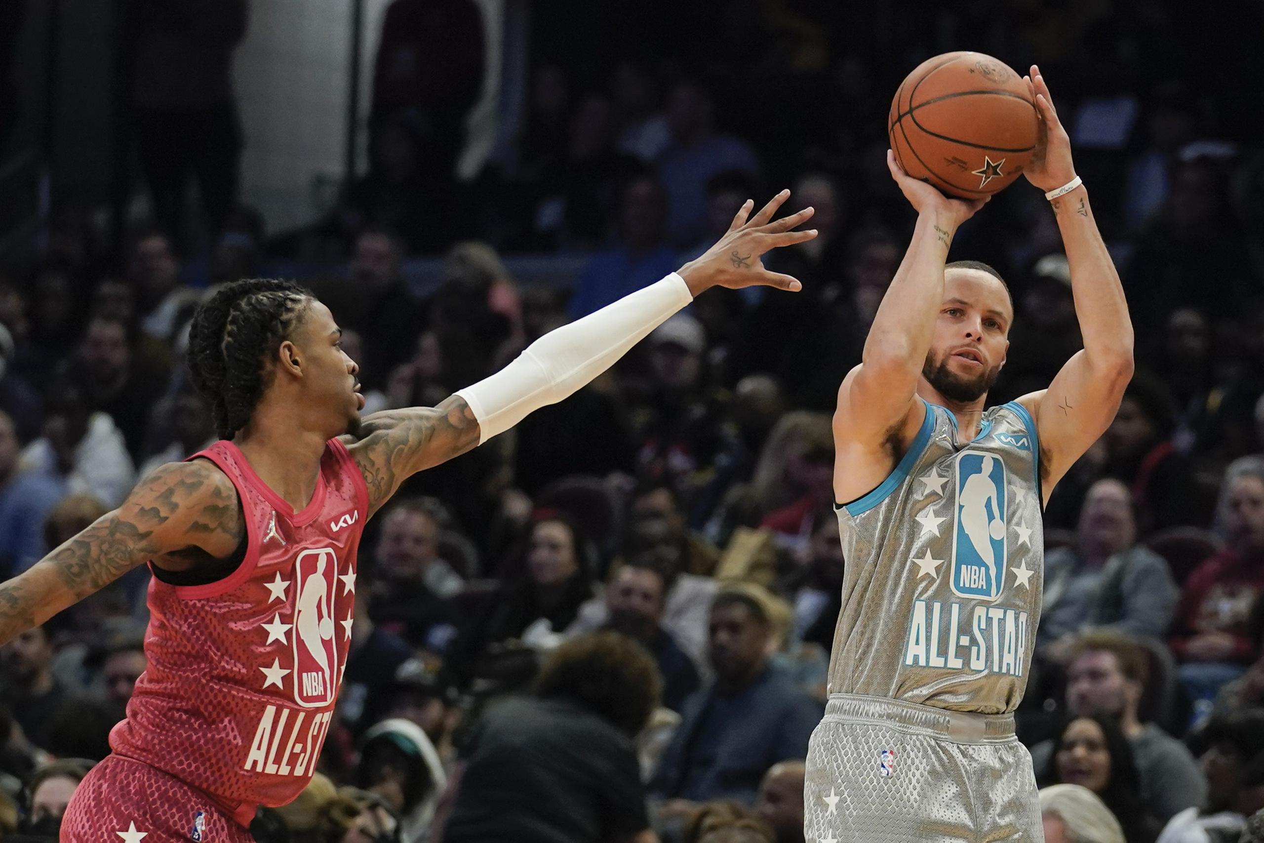 Stephen Curry, derecha, de los Warriors de Golden State, intenta un triple ante la marcación de Ja Morant, de los Grizzlies de Memphis, en el Juego de Estrellas de la NBA.