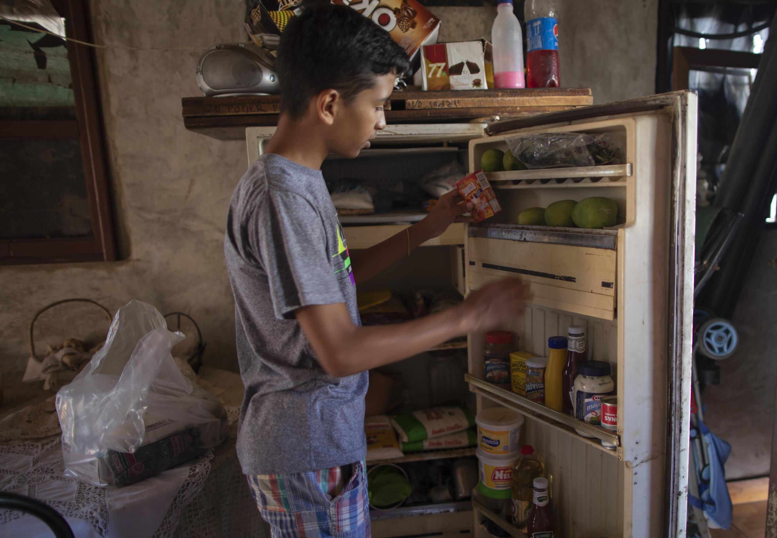 Samuel Andrés Mendoza, de 14 años, coloca sus bocadillos en un refrigerador deteriorado en su casa en Barquisimeto, Venezuela, el martes 2 de marzo de 2021.
