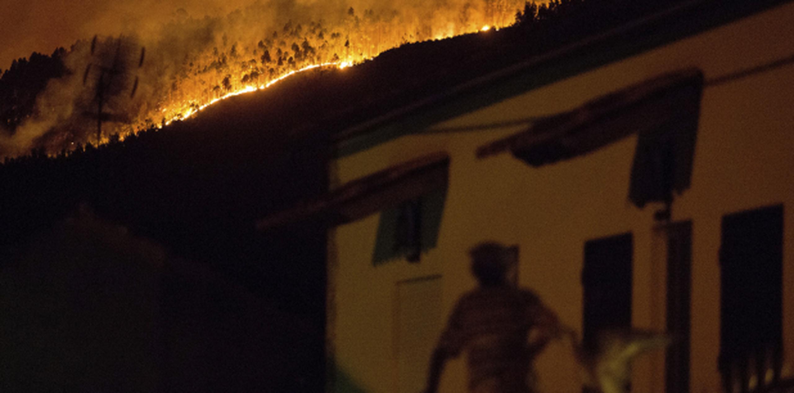 Un hombre observa desde su balcón las enormes llamas del incendio forestal. (AP)
