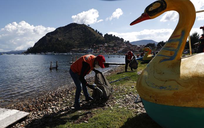 Voluntarios recolectan botellas de plástico de las orillas del lago Titicaca durante una campaña de limpieza para conmemorar el Día de la Tierra, en Copacabana, Bolivia, el jueves 22 de abril de 2021.