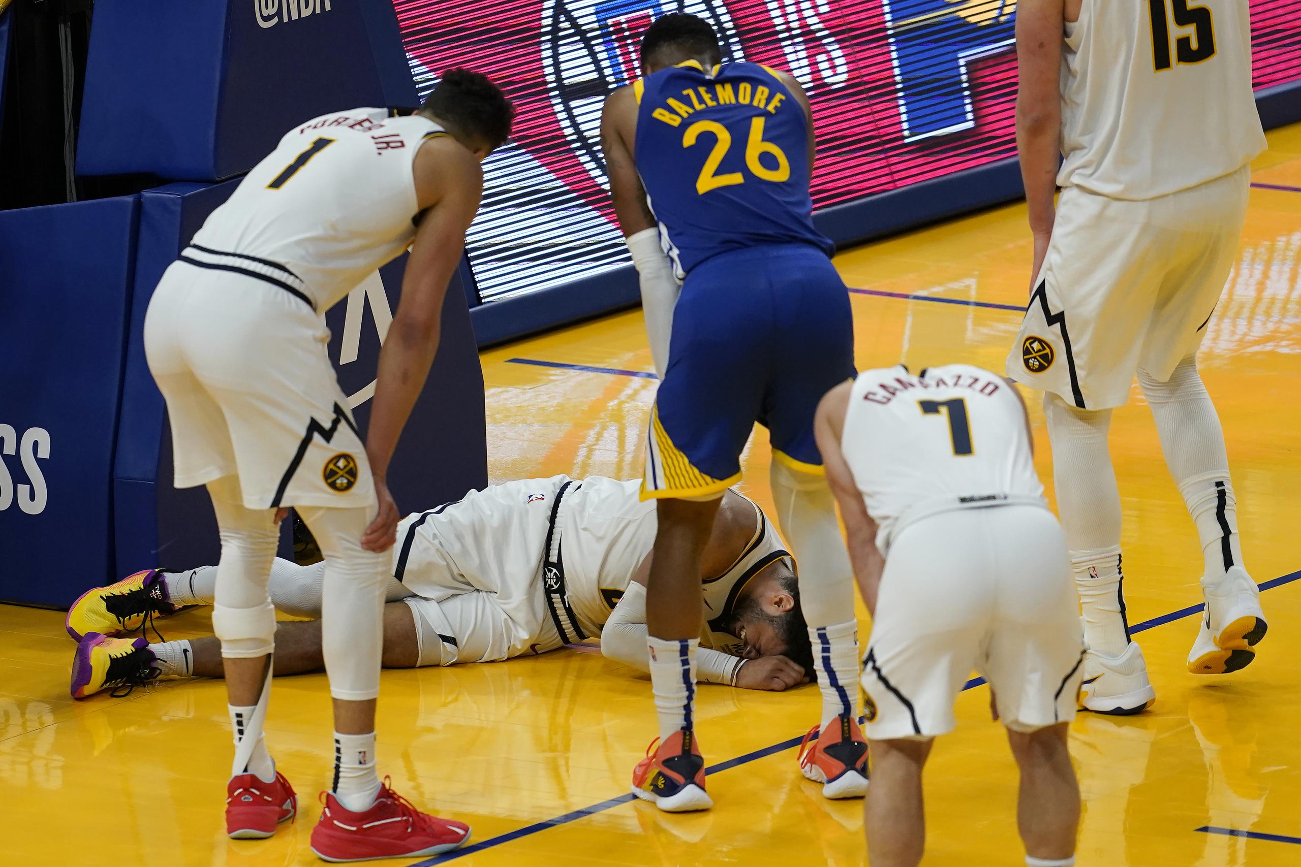 Jugadores de los Nuggets observan mientras Jamal Murray permanecía en el suelo después de sufrir una lesión en el minuto final del encuentro del lunes.
