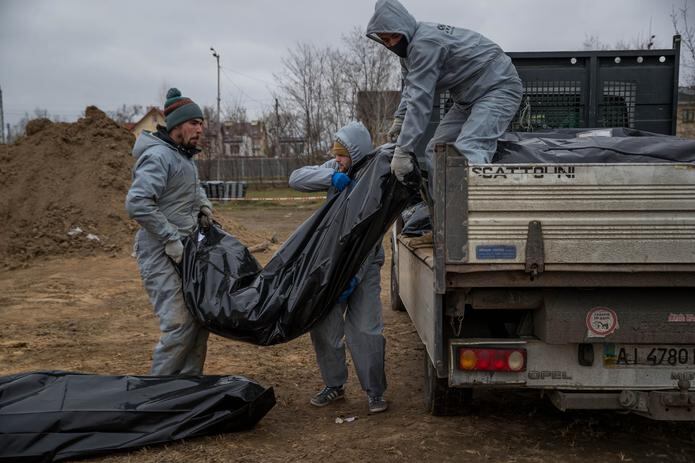 Autoridades forenses recogen cadáveres envueltos en plásticos para su traslado a la morgue en Bucha, en Ucrania, en una imagen de archivo. (EFE/ Miguel Gutiérrez)