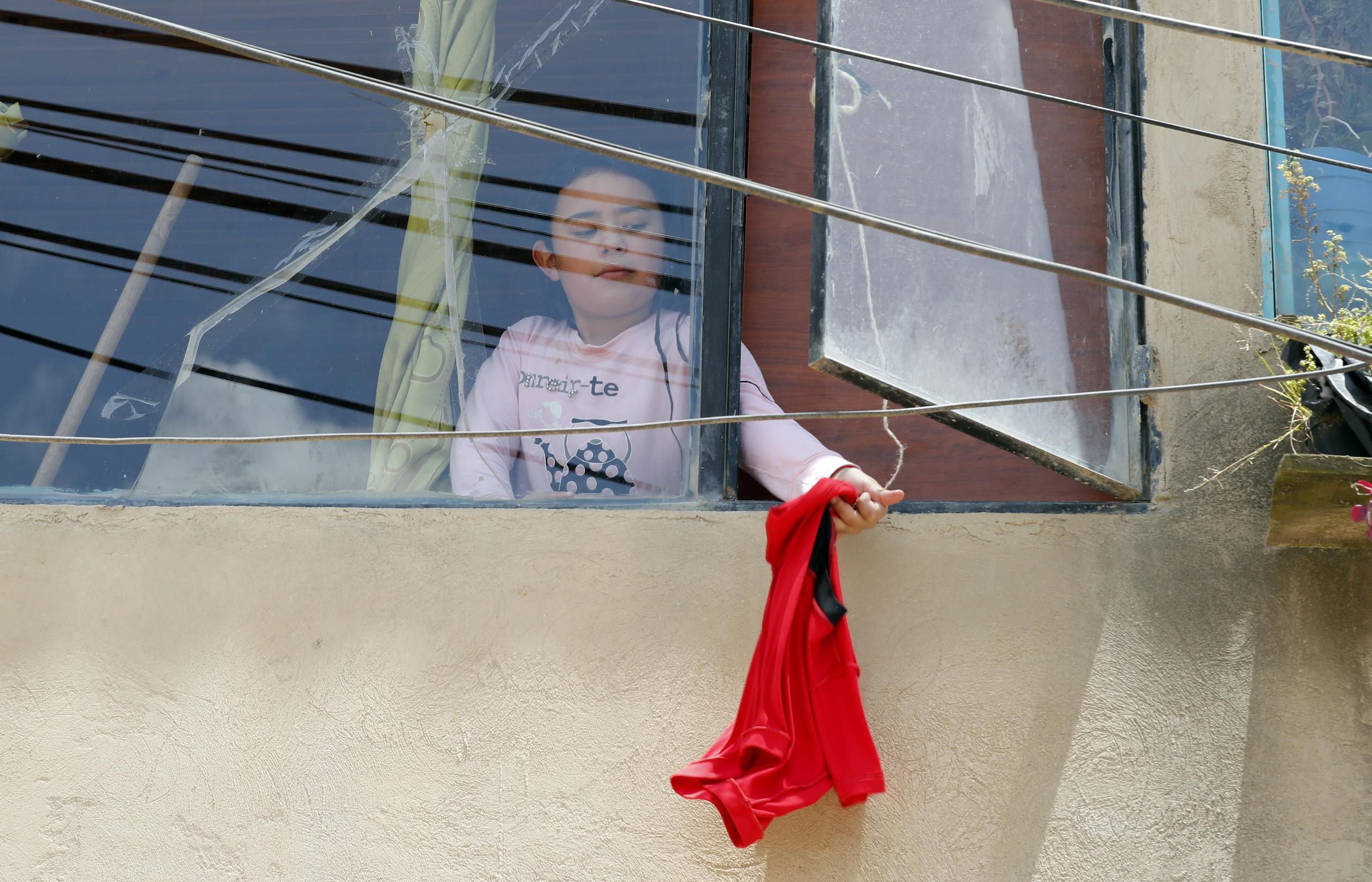 Una niña quita una trapo rojo de su ventana