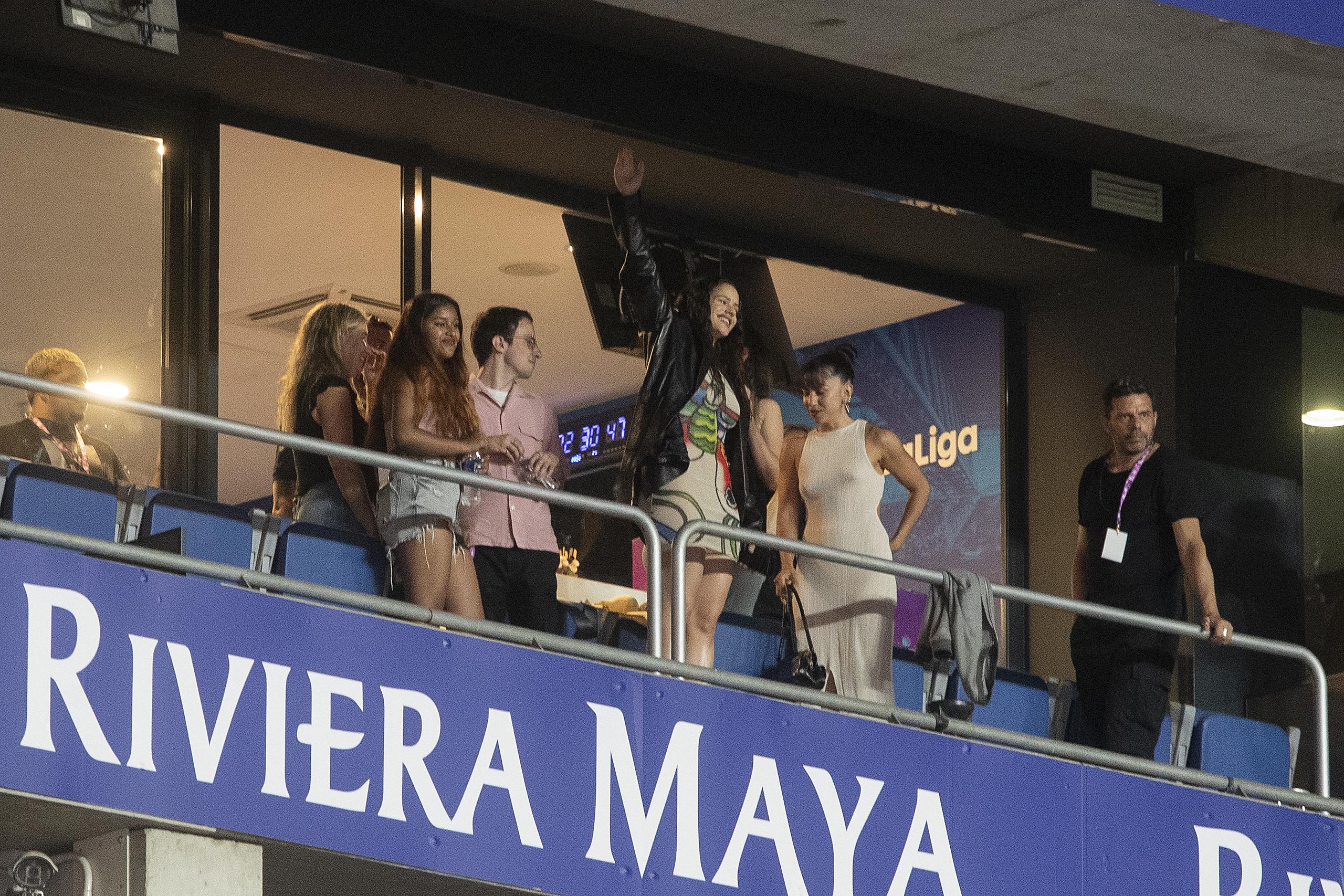La cantante Rosalía (3-d) saluda a la grada minutos antes de la actuación de su pareja, el cantante puertorriqueño de música urbana Rauw Alejandro, durante el concierto "Oh My Gol!" que organiza LaLiga celebrado este sábado en el RCDE Stadium, en Barcelona. (EFE/Marta Pérez)