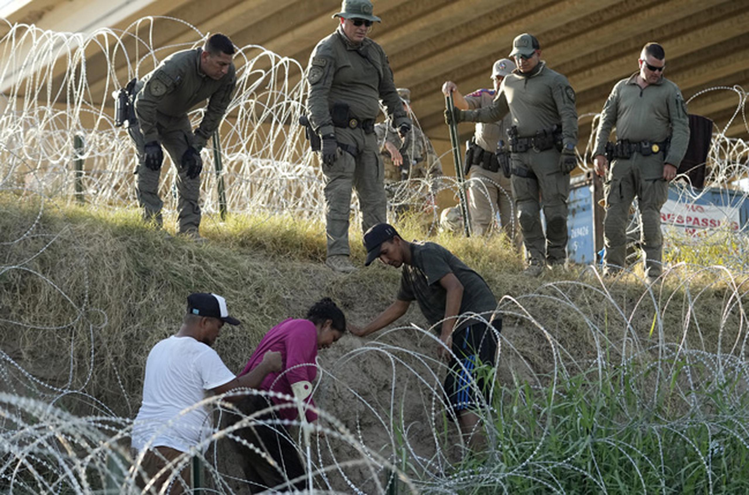 Soldados y guardias de Texas ayudan a una migrante que quedó atrapada en un alambre de púas después de cruzar el Río Grande desde México hacia EEUU, el 1 de agosto de 2023, en Eagle Pass, Texas. (Foto AP/Eric Gay)