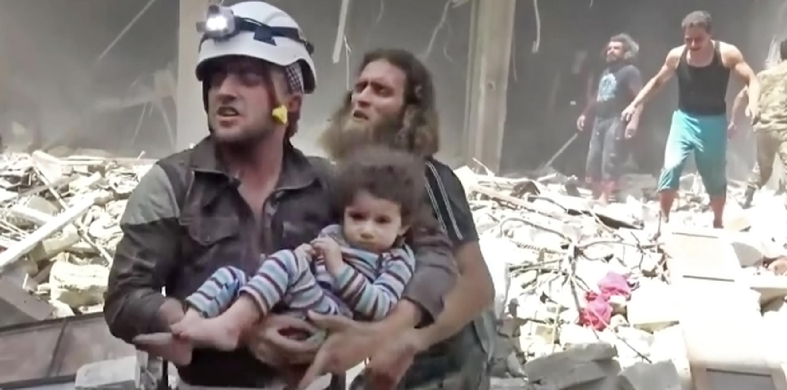 Un trabajador de la Defensa Civil siria rescata un menor de los escombros de un edificio bombardeado en la ciudad de Alepo. (Validated UGC via AP video)
