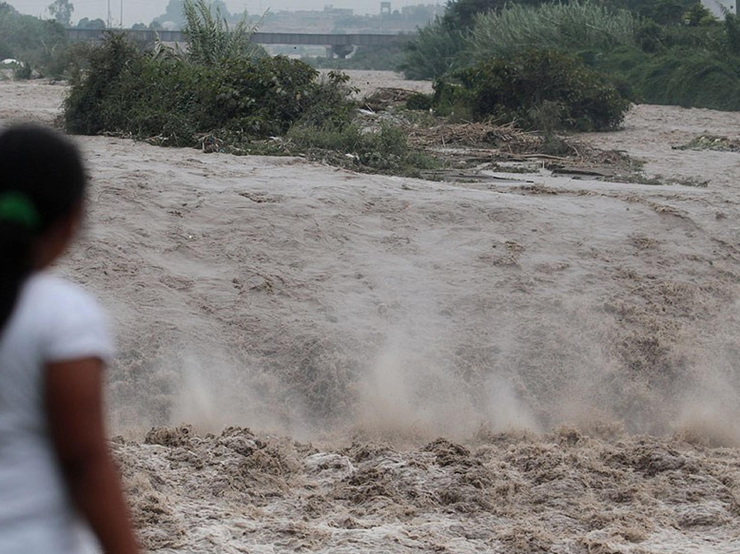 Una mujer observa la crecida de un río en Perú. (GDA)