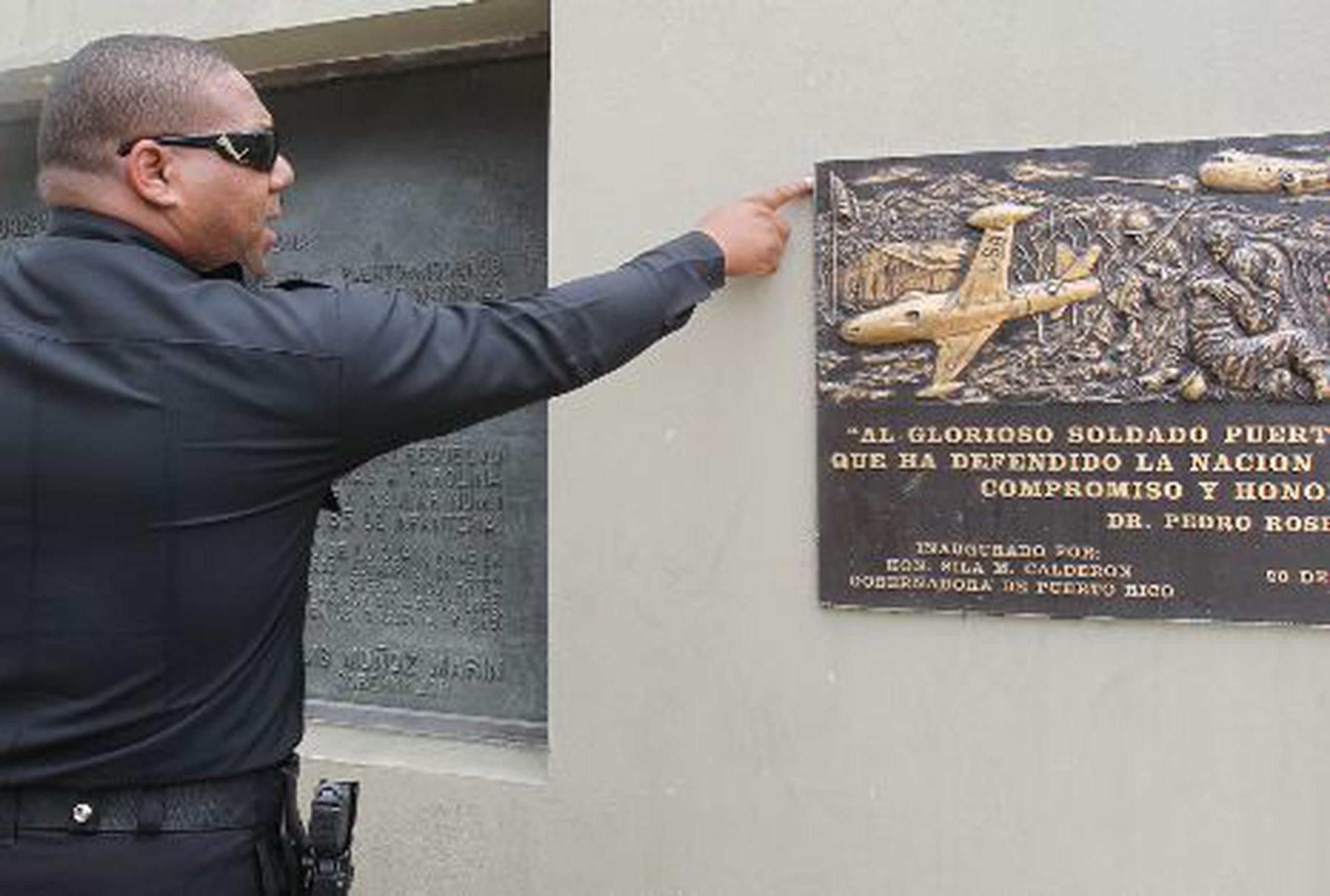 El oficial Jesús Andino García protege el monumento en honor al Regimiento 65 de  Infantería para que no le roben la tarja de cobre. <font color="yellow">(Primera Hora / Gerald López-Cepero)</font>