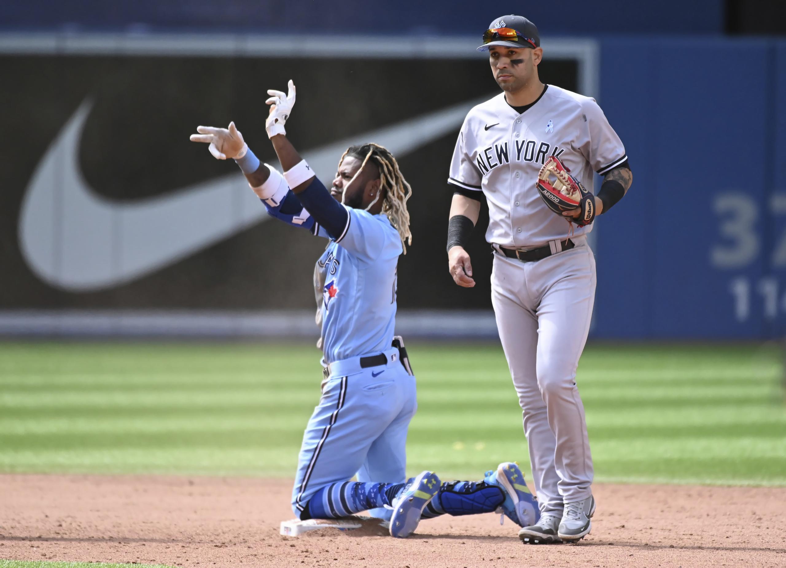 El jardinero derecho de Blue Jays de Toronto, Raimel Tapia, celebra con el dugout después de llegar safe en segunda base con barrida, evitando el toque de Marwin González, derecha, de los Yankees, para conseguir un doblete en la sexta entrada del juego de béisbol en Toronto.