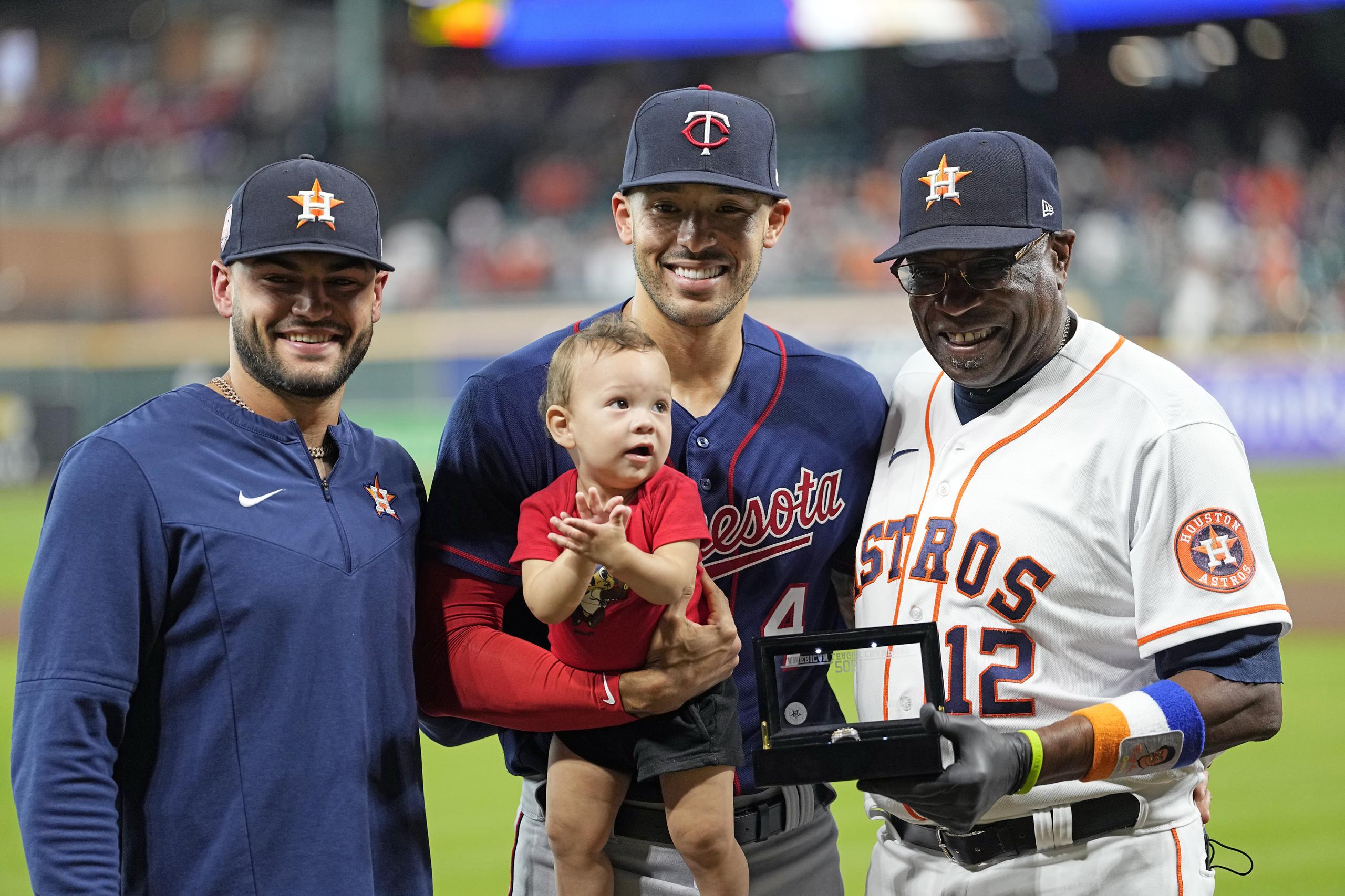 Carlos Correa (4), con su hijo Kylo, posa junto a Lance McCullers Jr. y el dirigente Dusty Baker Jr., estos últimos dos de los Astros, previo al juego de anoche, el primer del boricua como Twin jugado en Houston.