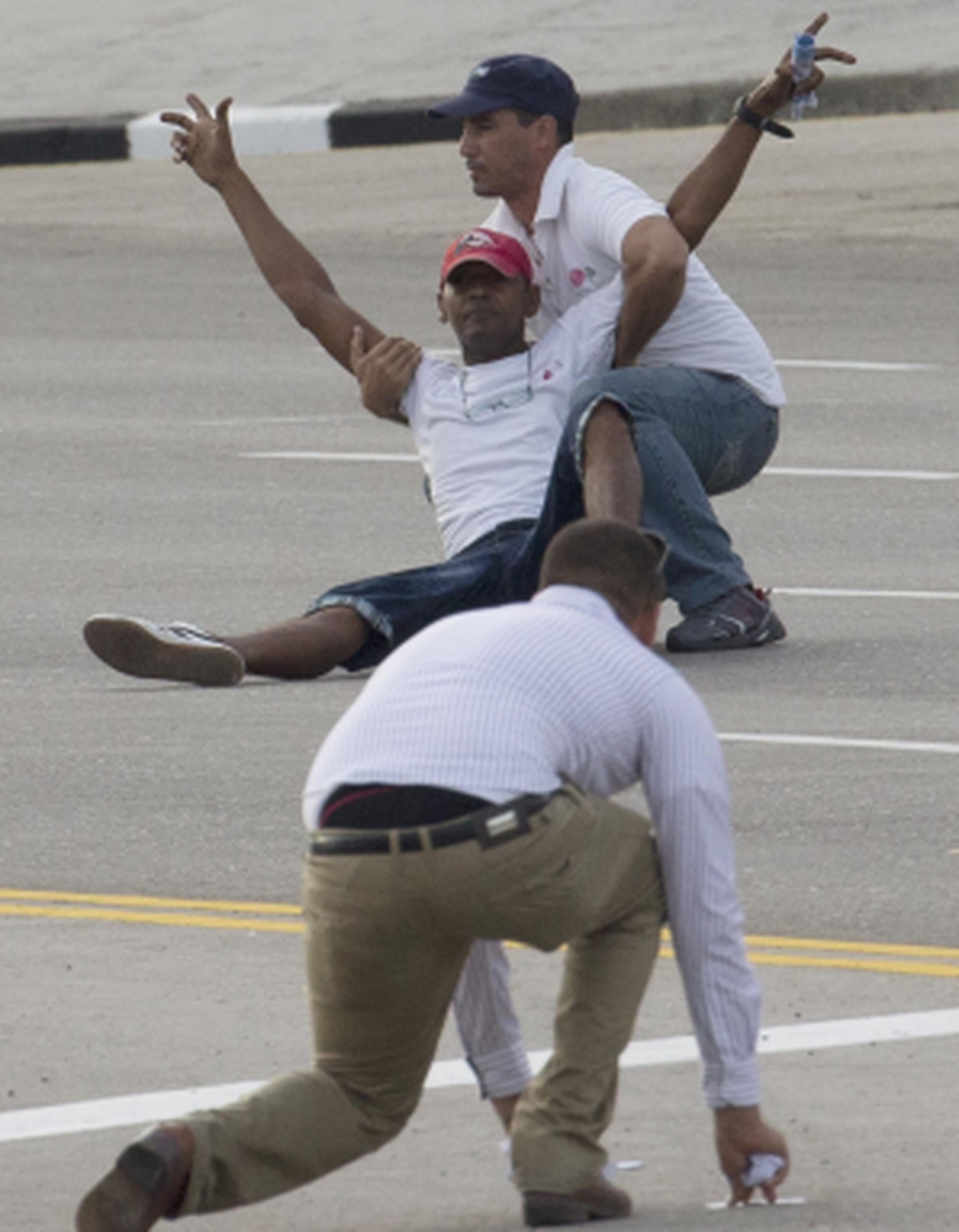 Oficiales de seguridad cubanos intervienen con un sujeto que lanzaba panfletos en la ruta del papa. (AP)