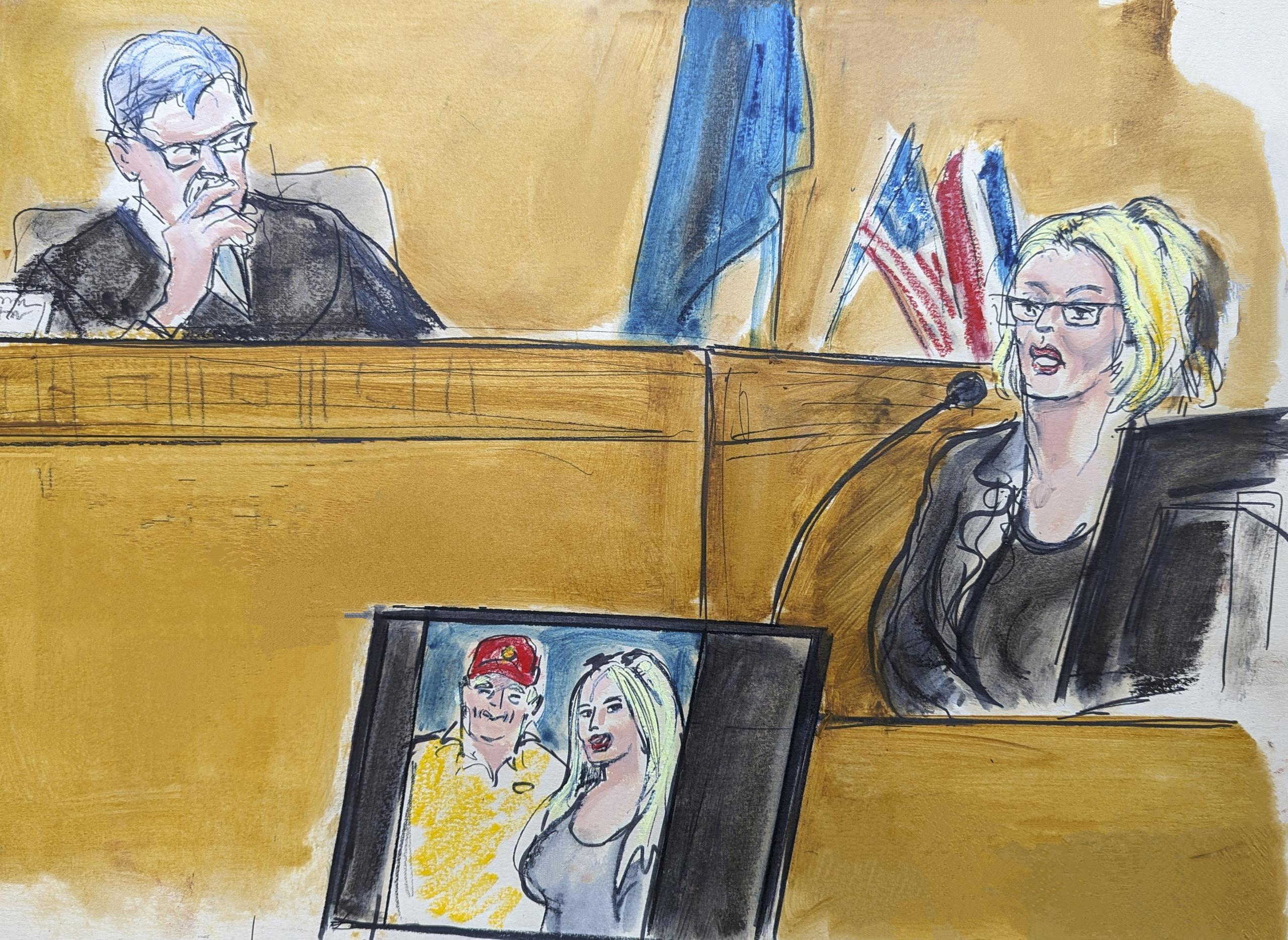 En este dibujo del tribunal, Stormy Daniels testifica en el estrado mientras el juez Juan Merchan observa, el martes 7 de mayo de 2024, en Nueva York. En una pantalla, se muestra una fotografía de Donald Trump y Daniels de su primer encuentro. (Elizabeth Williams vía AP)