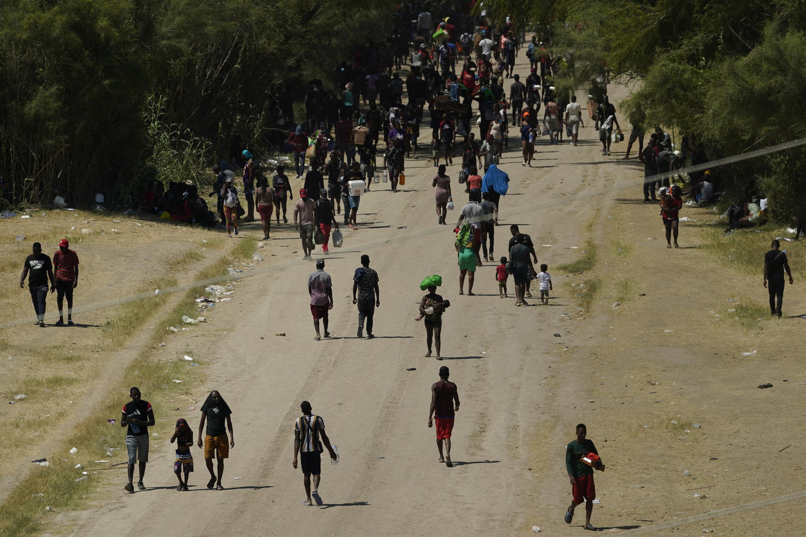 Migrantes haitianos caminan por un camino de tierra después de ingresar a Estados Unidos desde México en Del Rio, Texas.