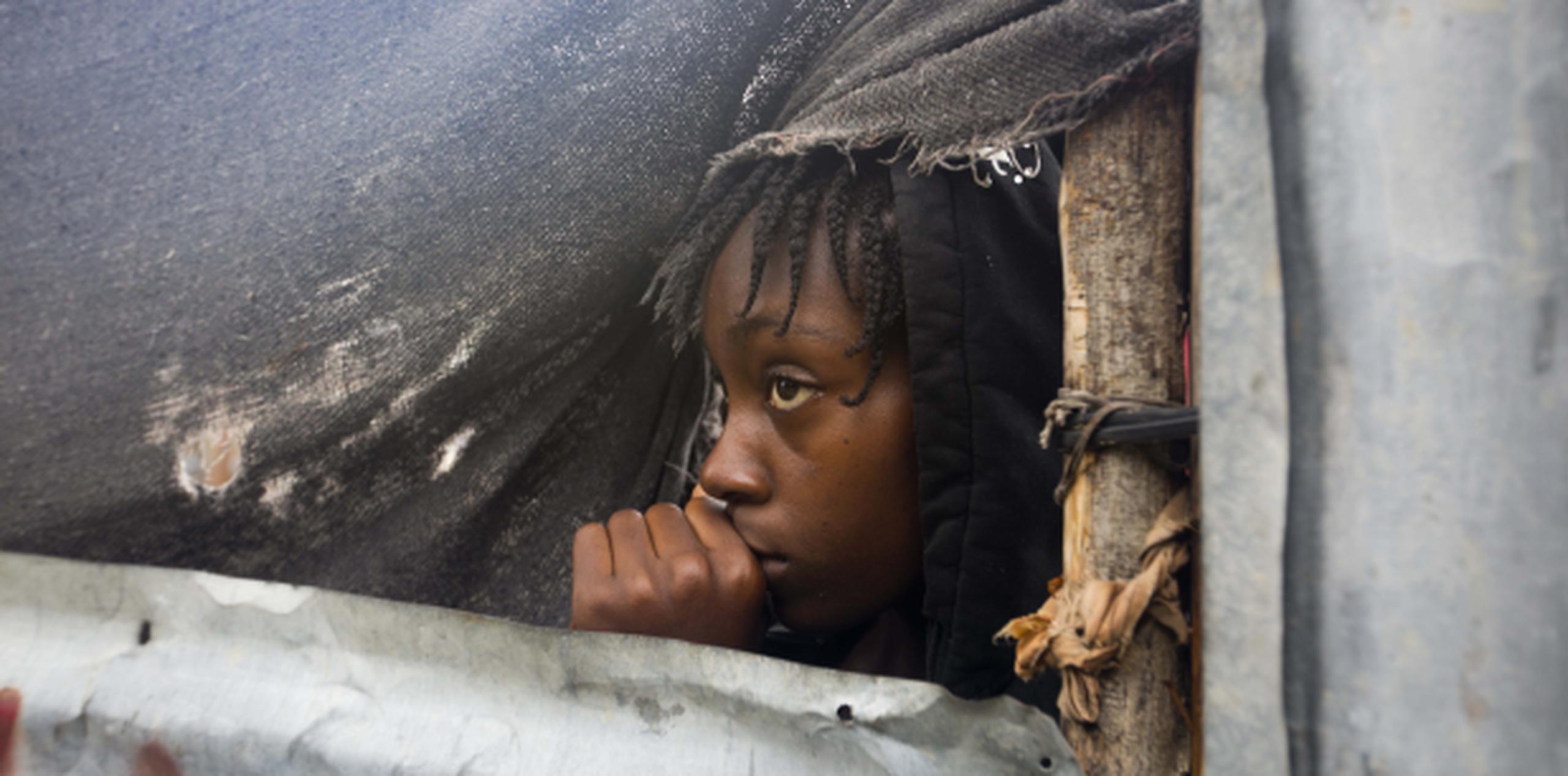 Una niña refugiada en Haití se asoma al exterior para observar las condiciones del clima. (Archivo)