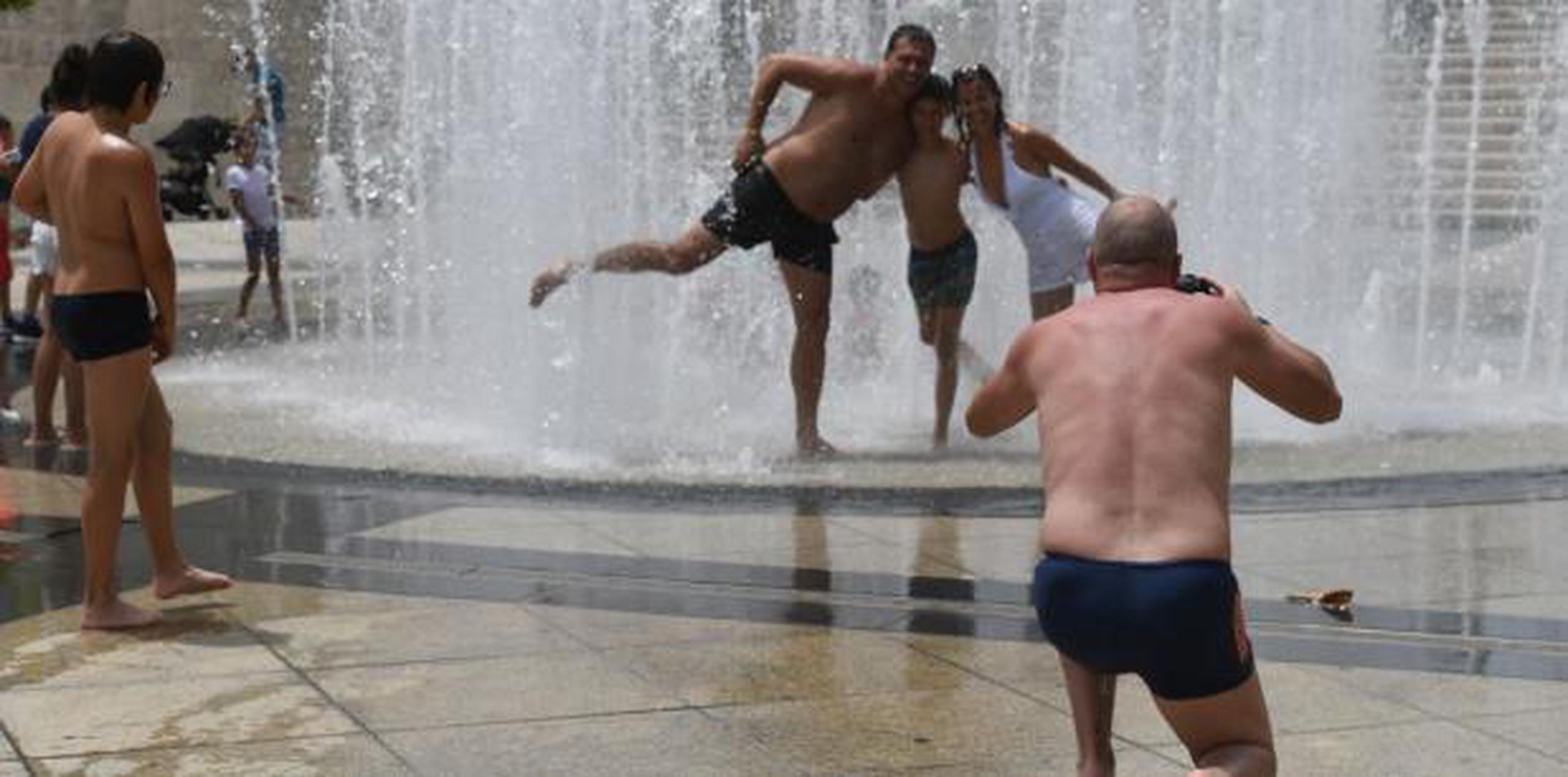 Grandes y pequeños disfrutan de un baño la famosa fuente ubicada en la Plaza del V Centenario. (luis.alcaladelolmo@gfrmedia.com)