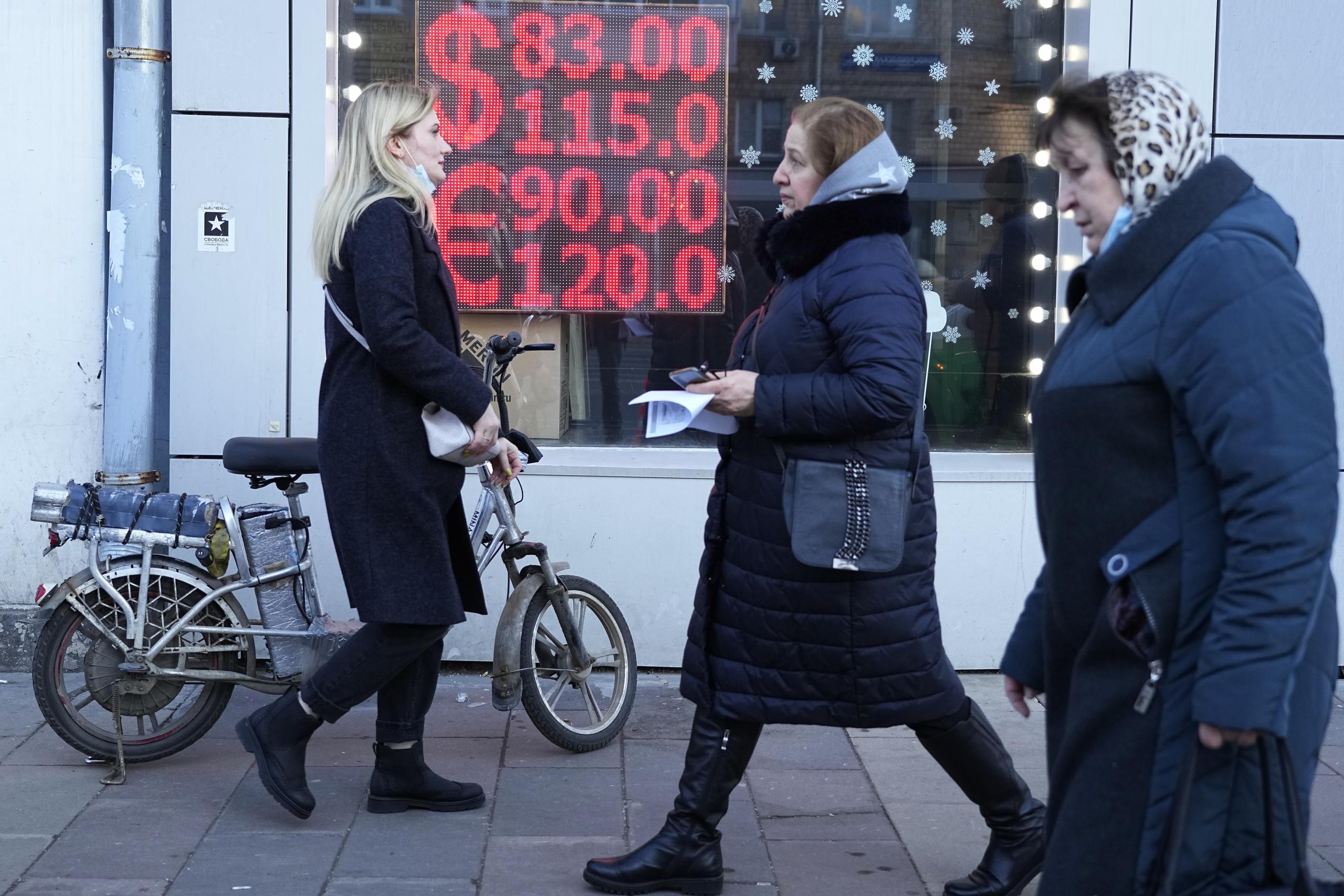 Unas personas caminan frente a una oficina de cambio de moneda que muestra el tipo de cambio del dolar y el euro a rublos rusos en Moscú, el 28 de febrero de 2022.  (AP Foto/Pavel Golovkin, Archivo)