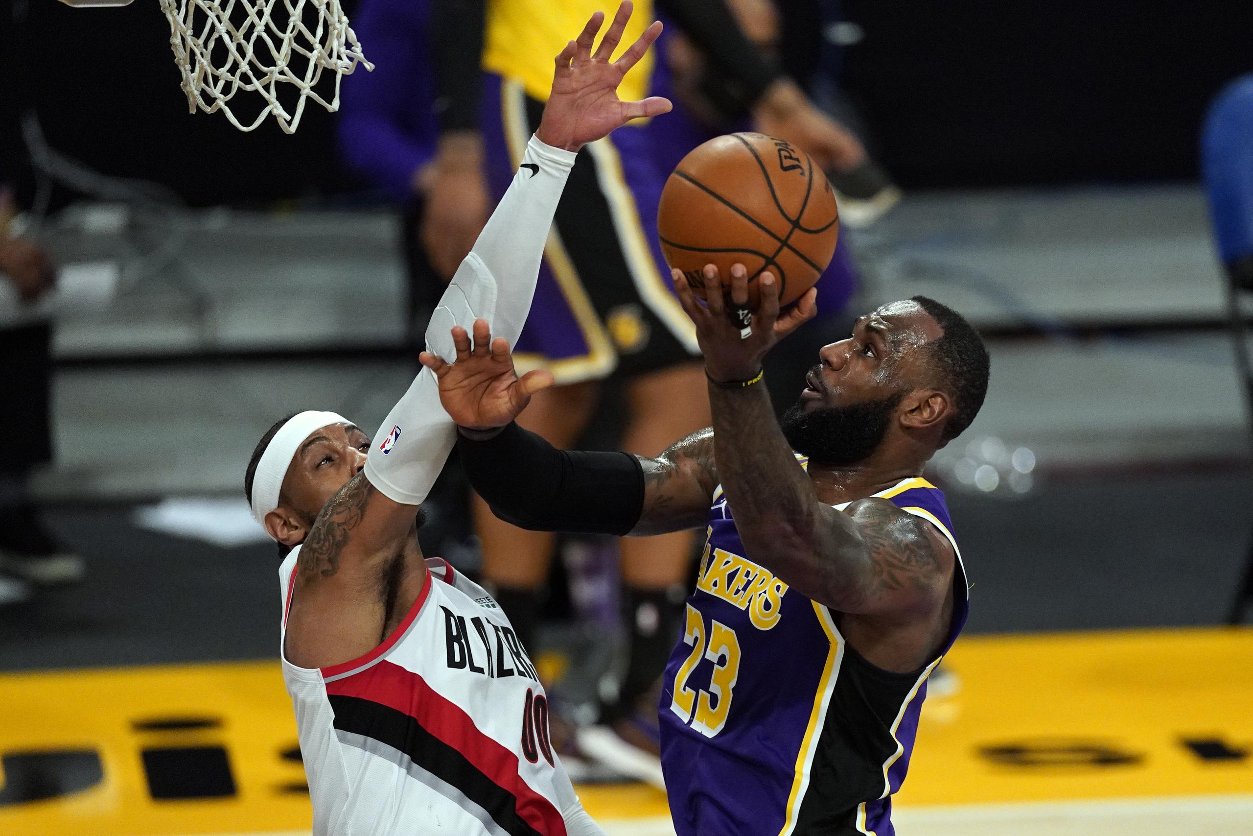 LeBron James, de los Lakers de Los Ángeles, intenta un tiro debajo del aro ante la defensa de Carmelo Anthony, de los Trail Blazers de Portland.