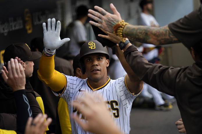 Juan Soto es felicitado por sus nuevos compañeros luego de que anotara una carrera durante el partido el miércoles, su debut con los Padres en San Diego Padres.