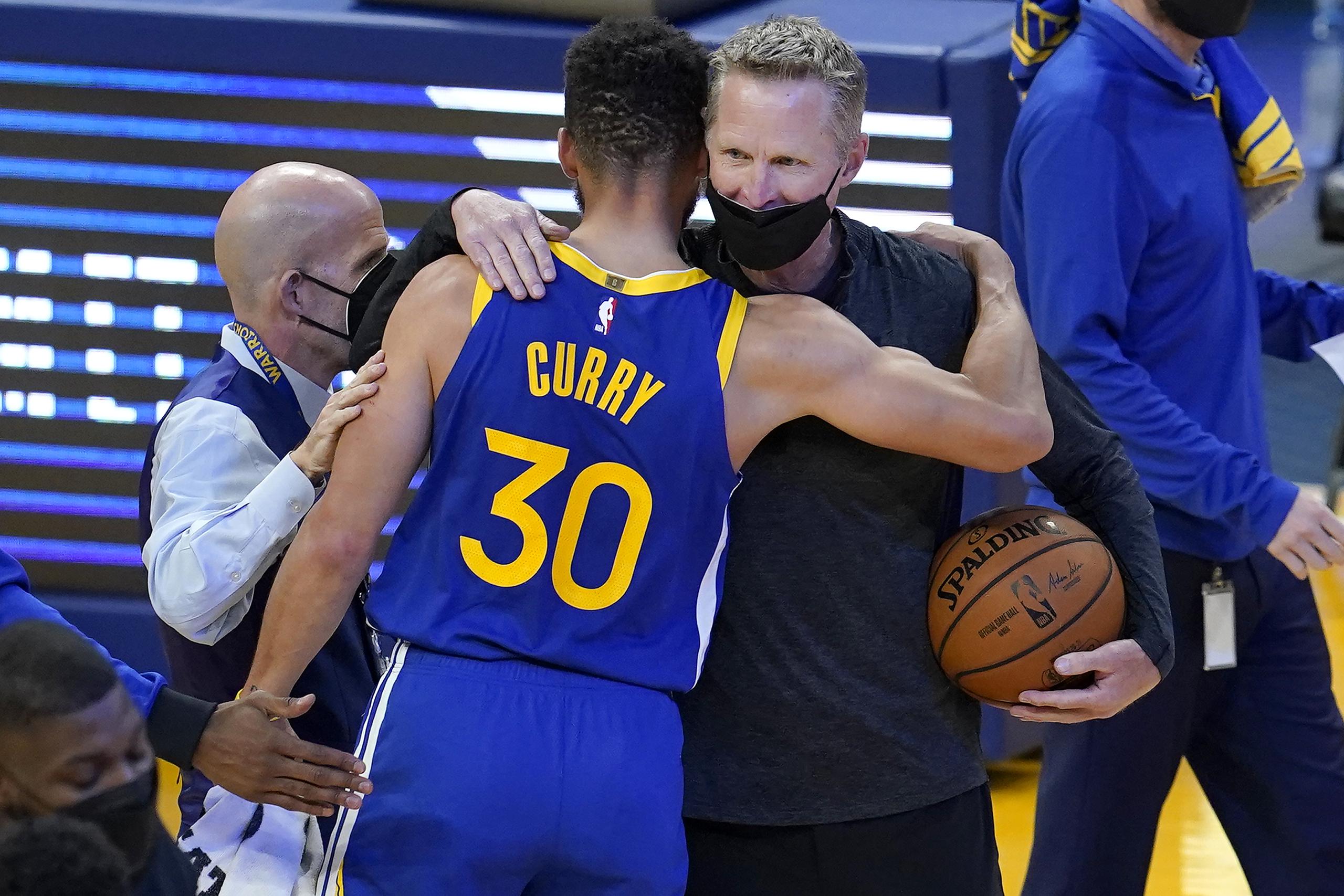 Stephen Curry de los Warriors de Golden State abraza al dirigente del equipo Steve Kerr.