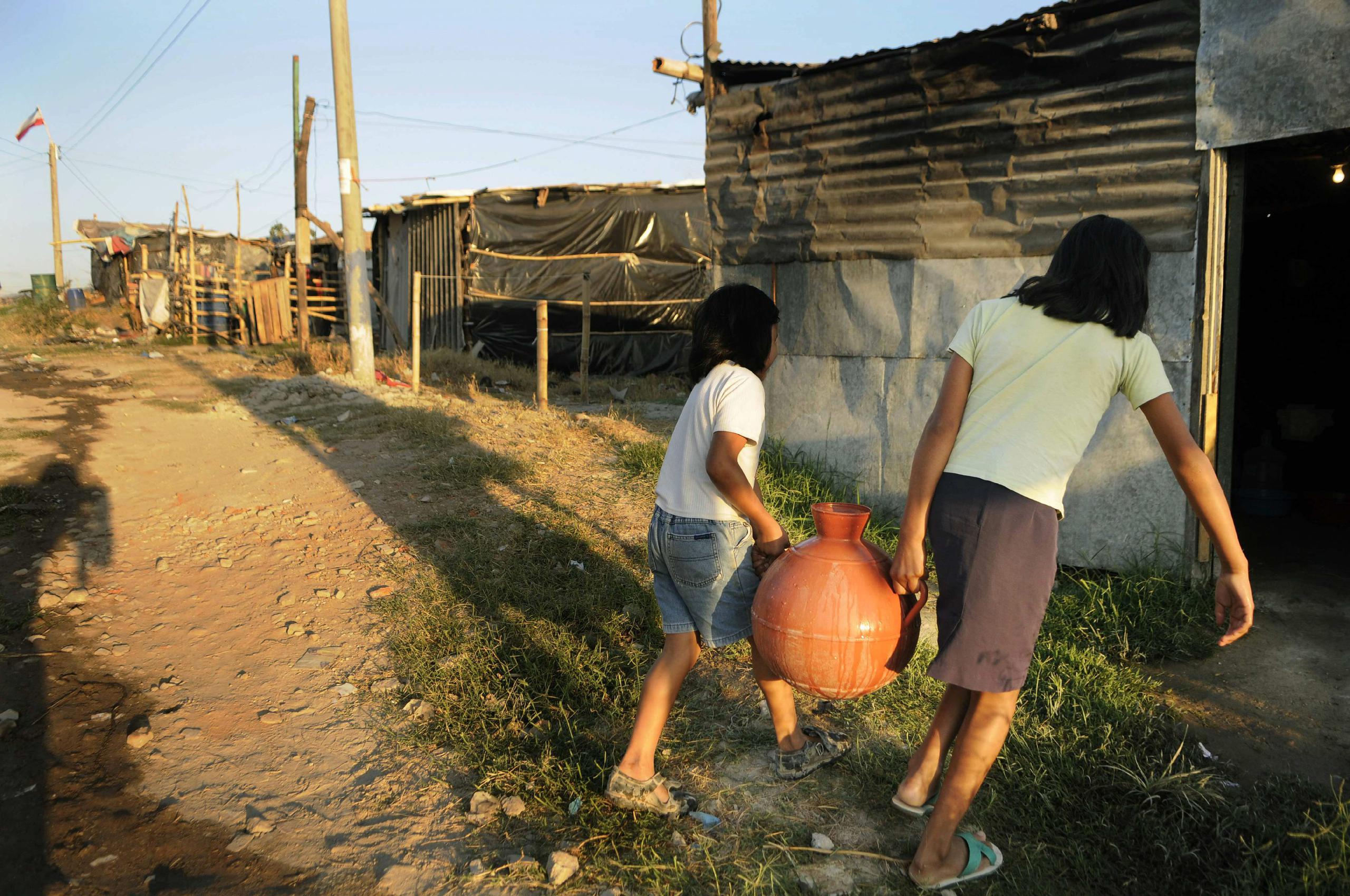 En El Salvador, al menos el 68 % de su agua superficial está contaminada y unas 500.000 personas (de más de 6 millones de habitantes) no tienen agua potable. En la imagen un registro de archivo de un par de mujeres al cargar un cántaro de agua hasta su casa que no cuenta con este servicio público, en Soyapango (El Salvador). EFE/Roberto Escobar
