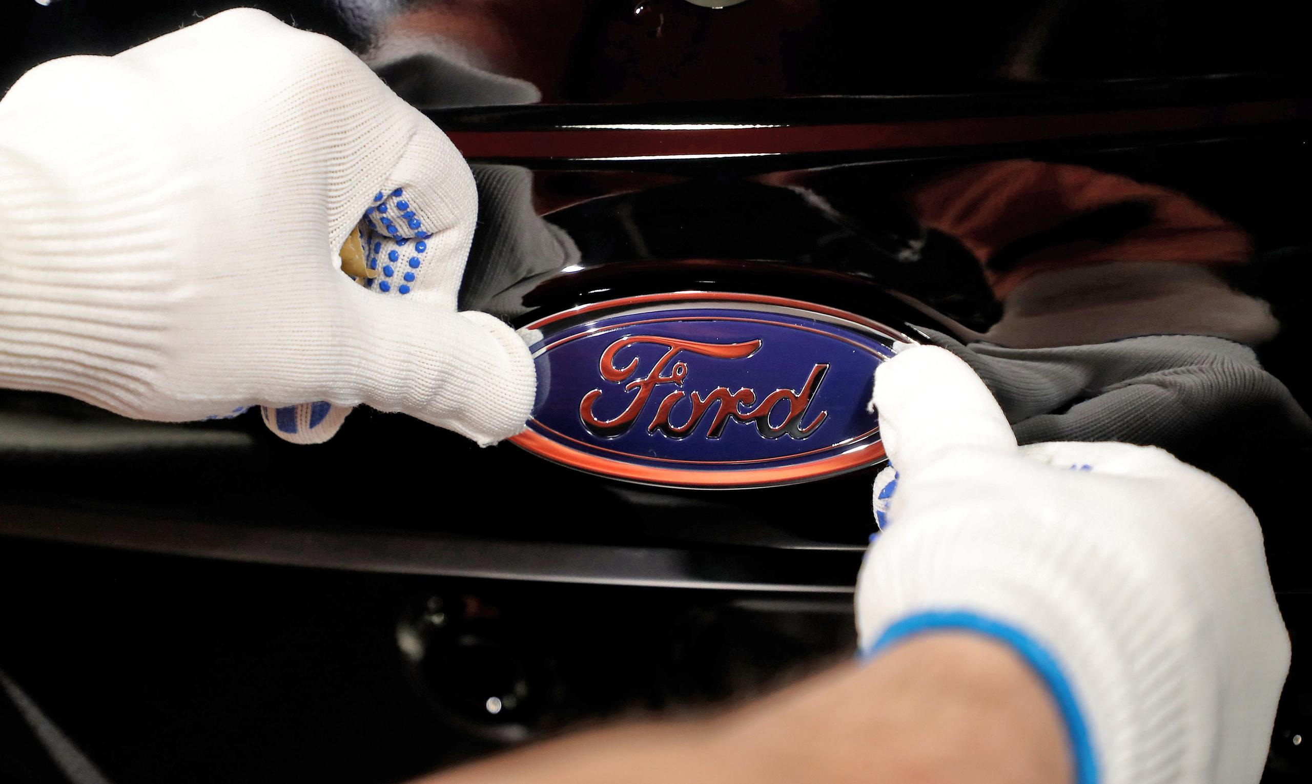 Fotografía de archivo que muestra a un empleado del fabricante de automóviles Ford mientras coloca el logotipo de la empresa en un vehículo en una planta de Colonia, Alemania. EFE/ Friedemann Vogel
