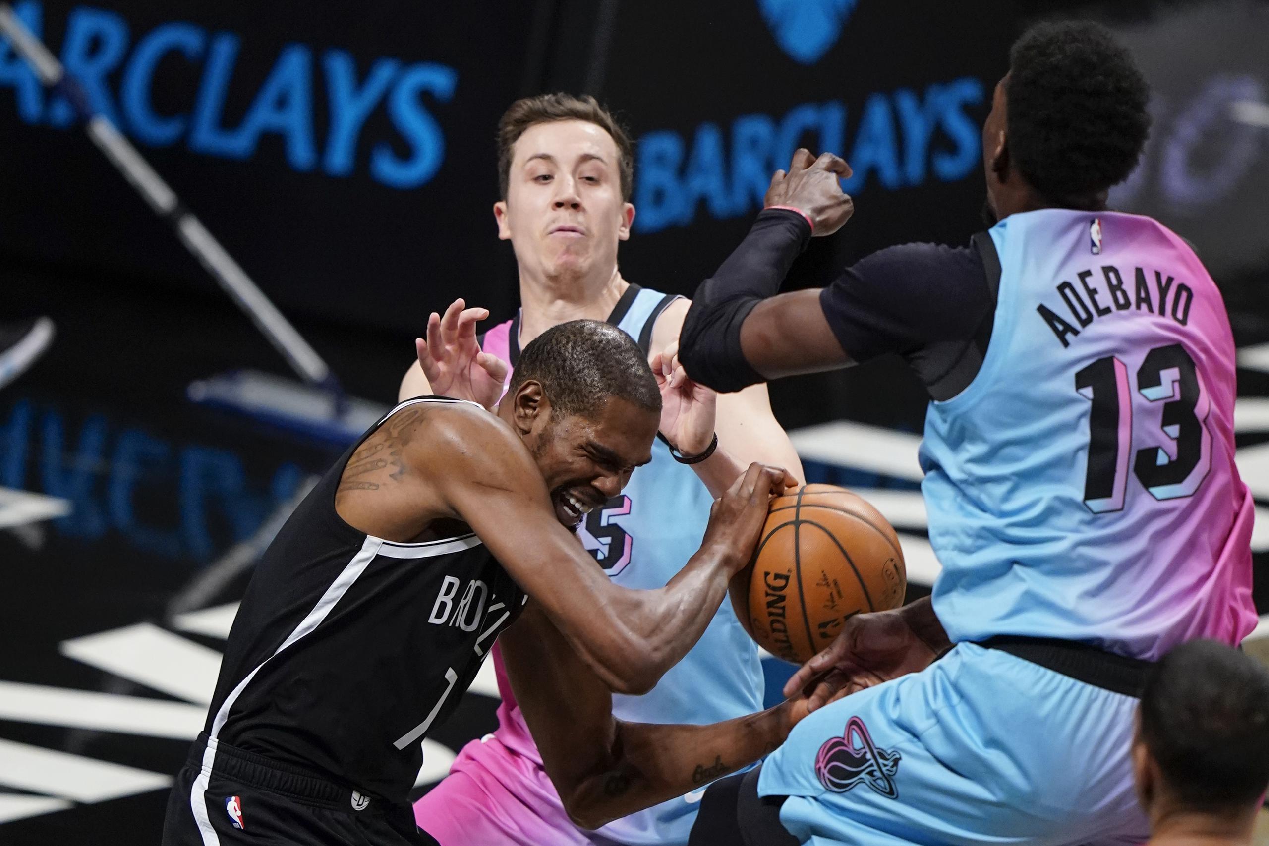 Kevin Durant, de los Nets de Brooklyn, se aferra al balón, entre Bam Adebayo y Duncan Robinson, del Heat de Miami, durante el duelo del sábado.