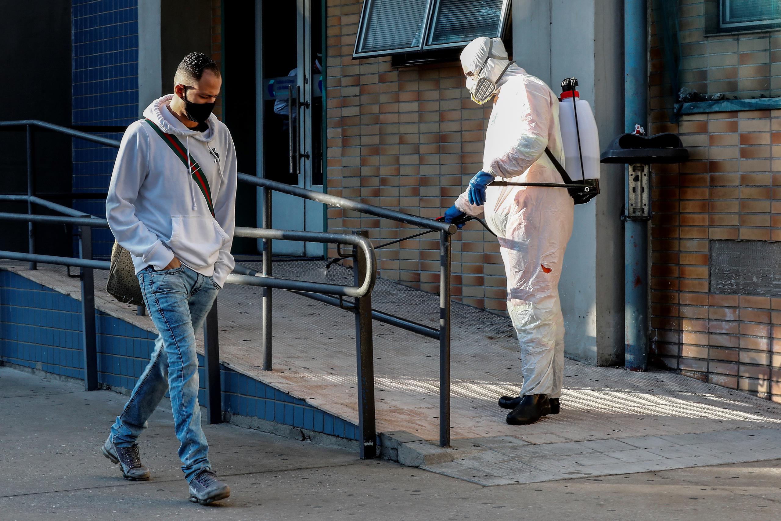 Un agente municipal desinfecta este jueves, la fachada de una unidad de salud en Sao Paulo.