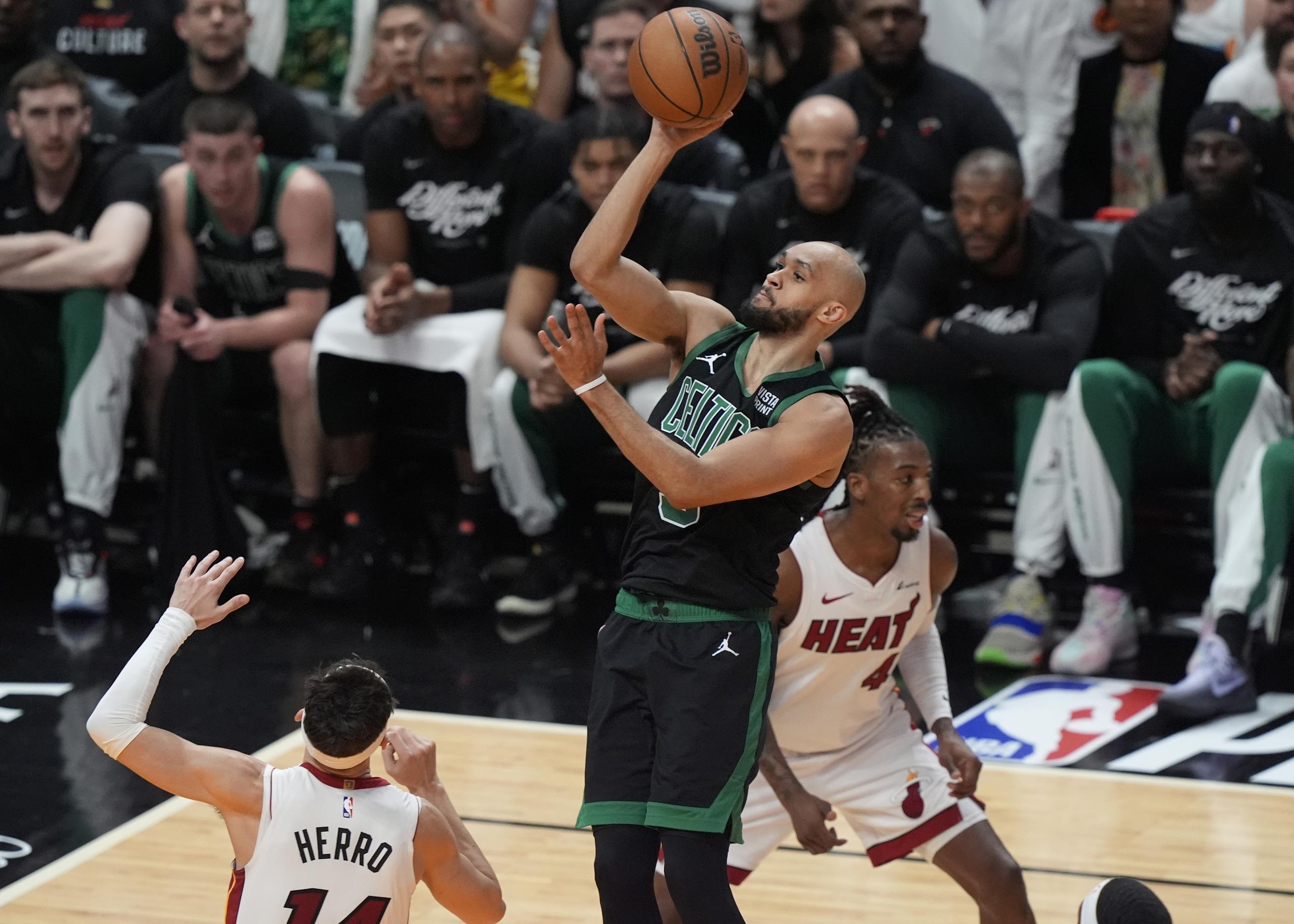 El escolta de los Celtics de Boston, Derrick White (9), anota sobre el escolta del Heat de Miami, Tyler Herro (14), durante la primera mitad del Juego 4 de un partido de primera ronda de baloncesto de la NBA.